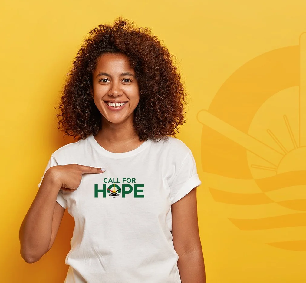 Smiling woman pointing to her white t-shirt with a political message against a yellow background with a faint sunburst graphic.
