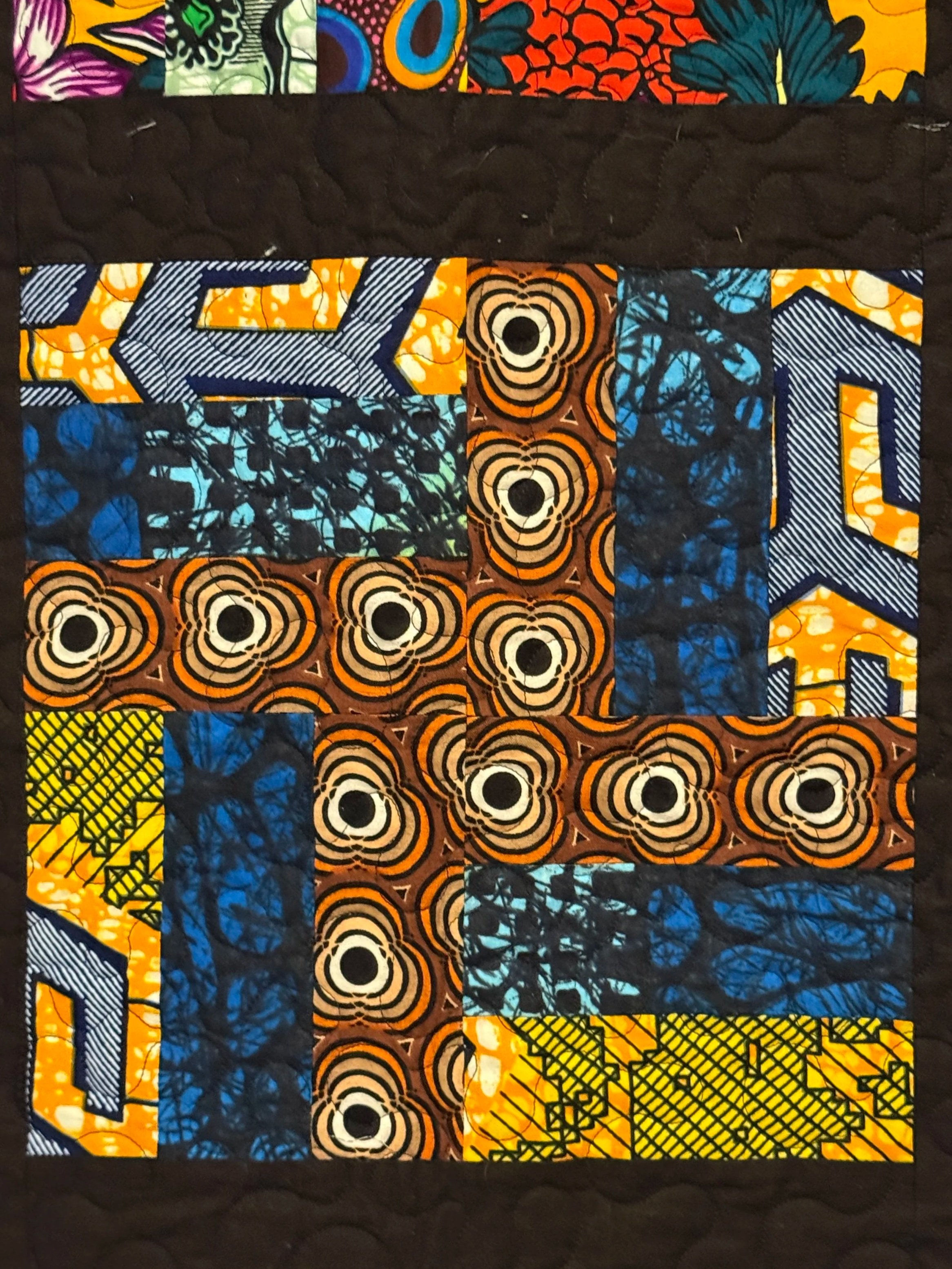 A colorful quilt with various patterned fabric pieces sewn together in a geometric design.