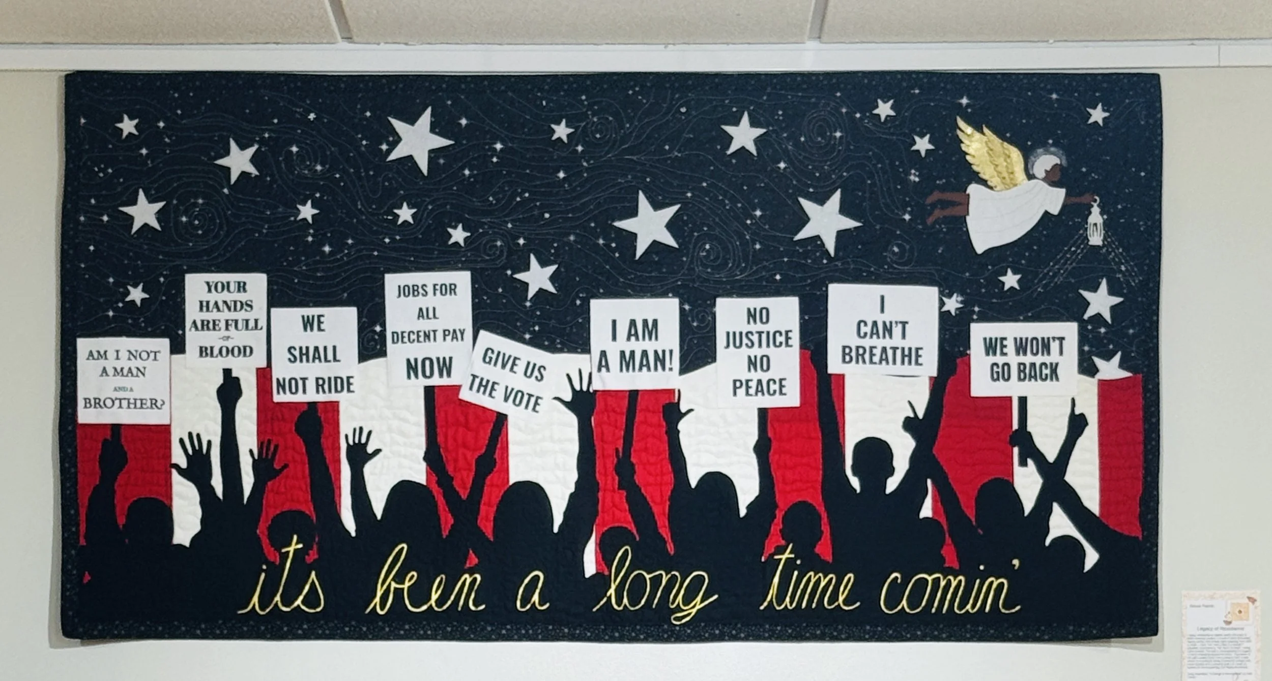A poster with a starry sky background and silhouettes of raised hands holding protest signs with messages about justice, voting, and equality. There is an angel with wings holding a lantern in the sky. Gold text at the bottom reads 'it's been a long time coming'.
