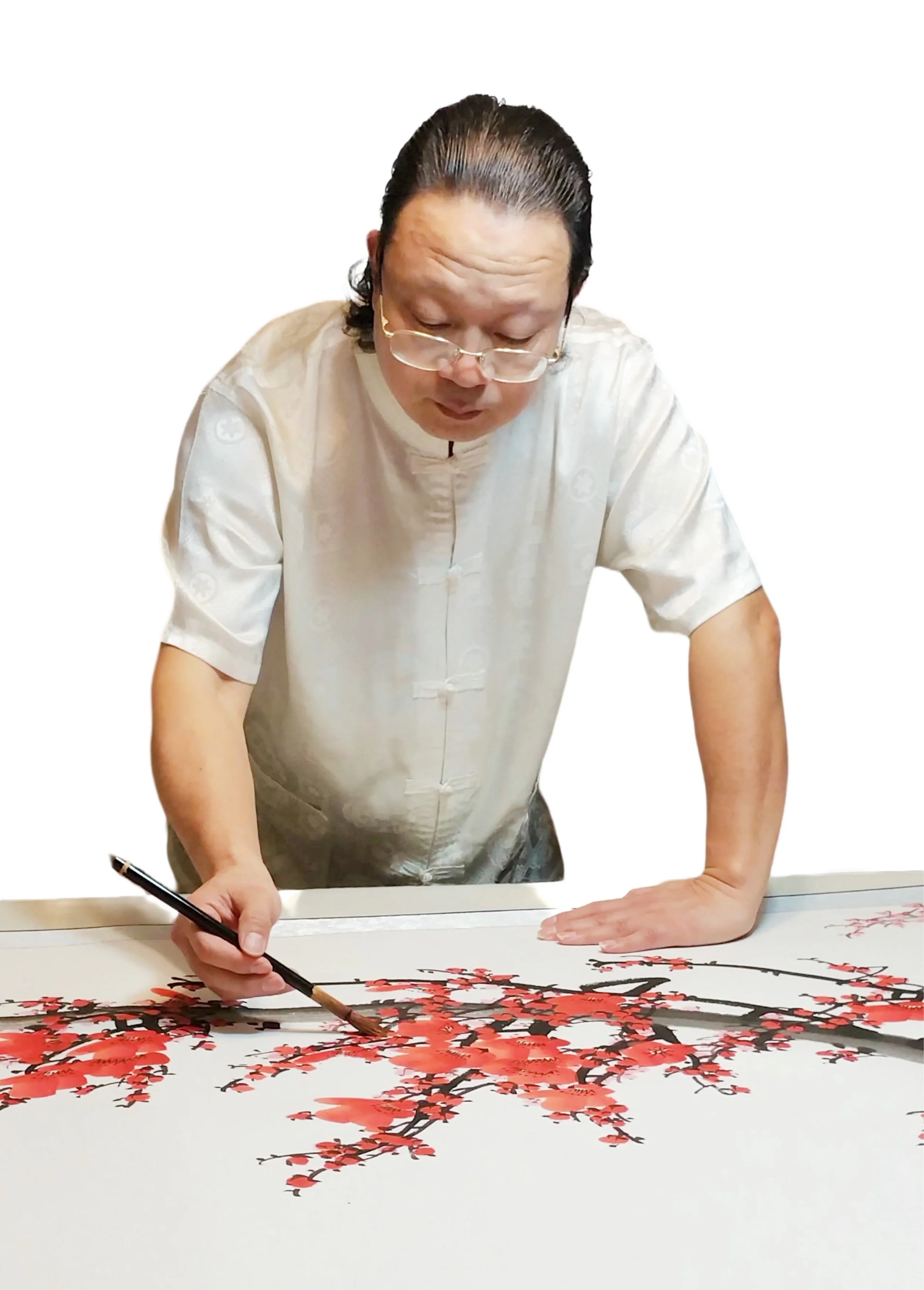 Artist wearing glasses and a traditional Asian shirt is painting a cherry blossom tree on a large white canvas using a brush with red and black paint.