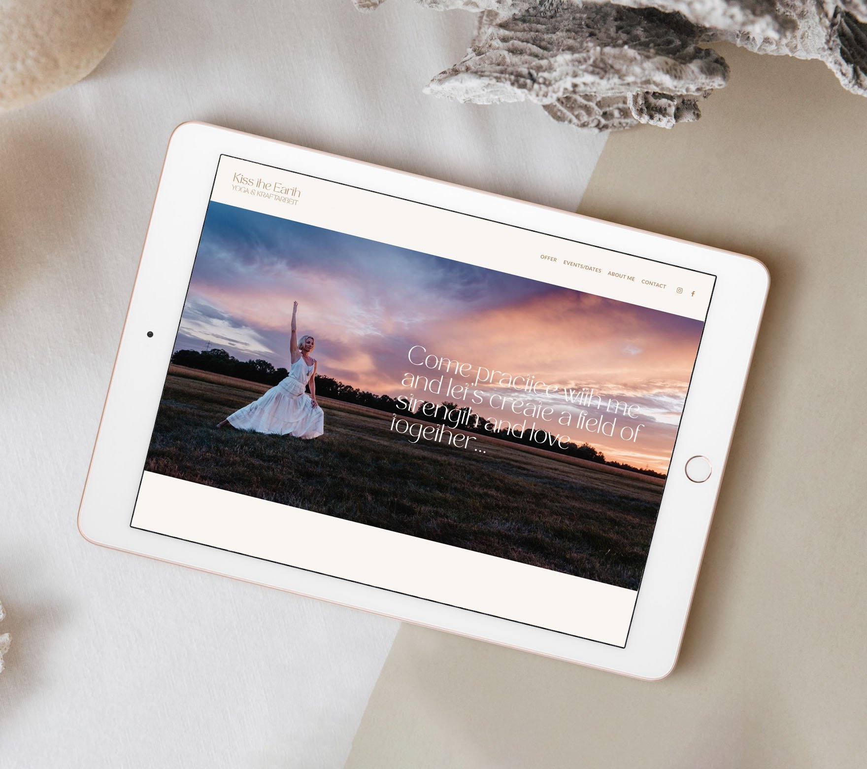 Tablet on a beige surface displaying a website with a woman in a white dress in a field at sunset, with navigation links at the top and a quote overlaying the image.
