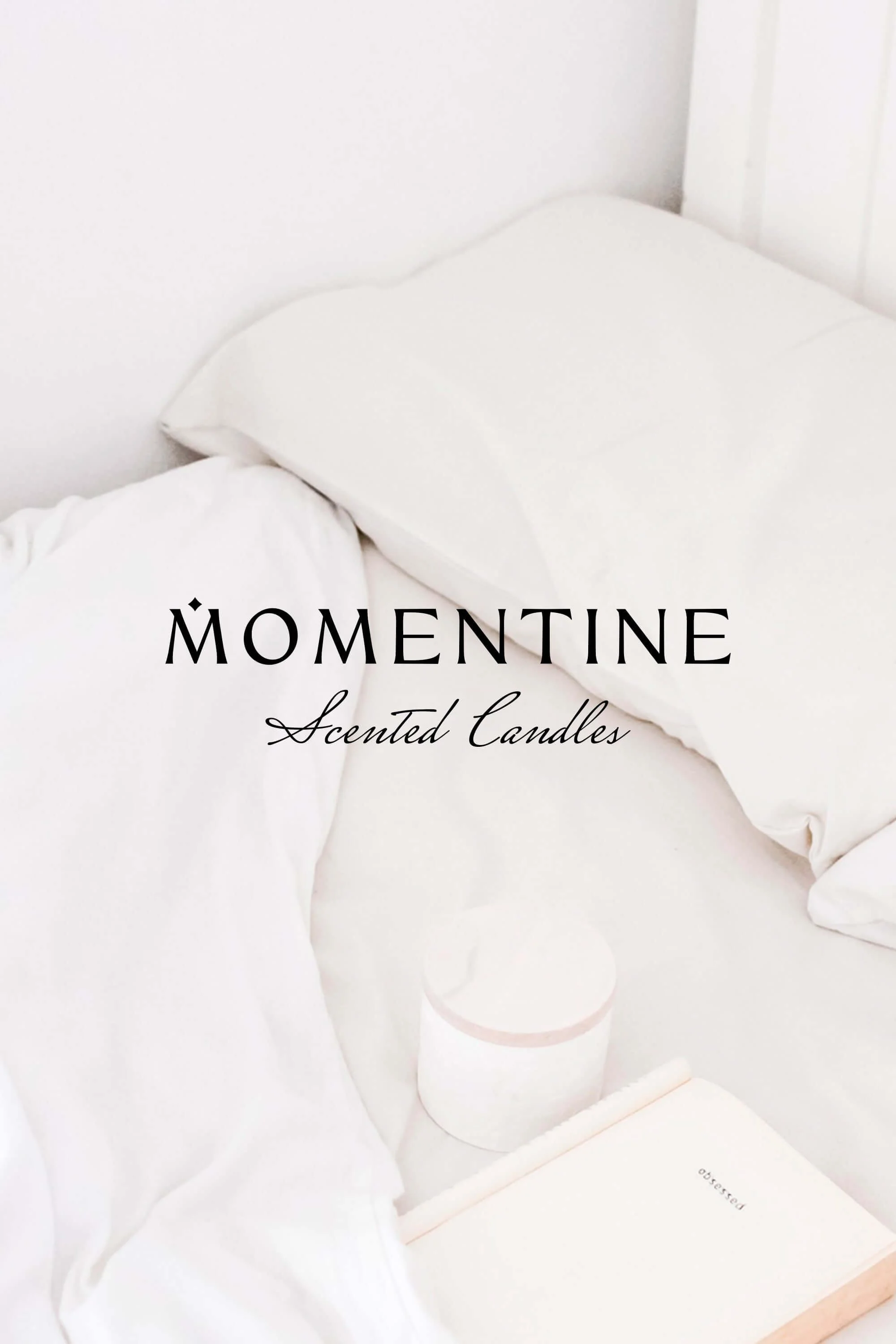 A neatly made bed with white pillows and sheets, a round white scented candle, and an open book on a white bedside table, creating a calm and minimalist aesthetic for scented candles.