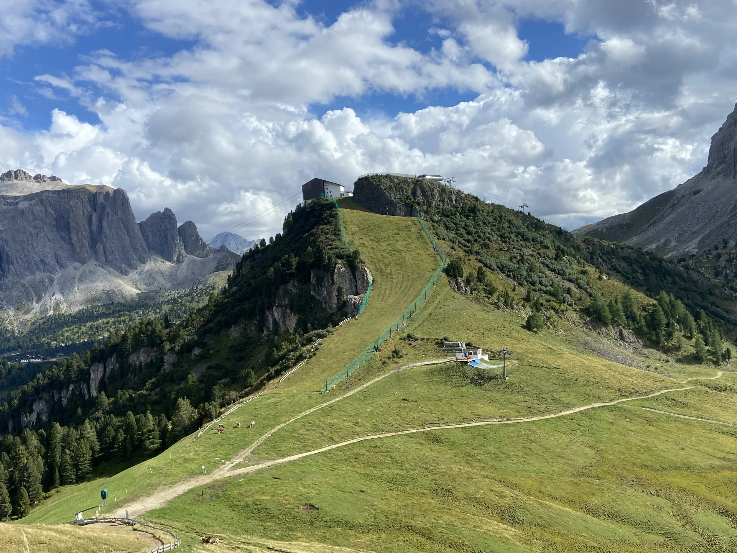 A mountainous landscape with green hills and a ski lift pathway.