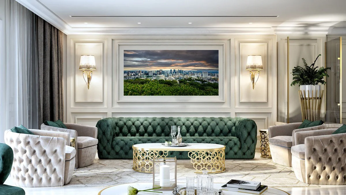 Elegant living room with green and beige tufted sofas, wall sconces, a large wall-mounted television displaying a cityscape, and a decorative plant in a gold and white planter.