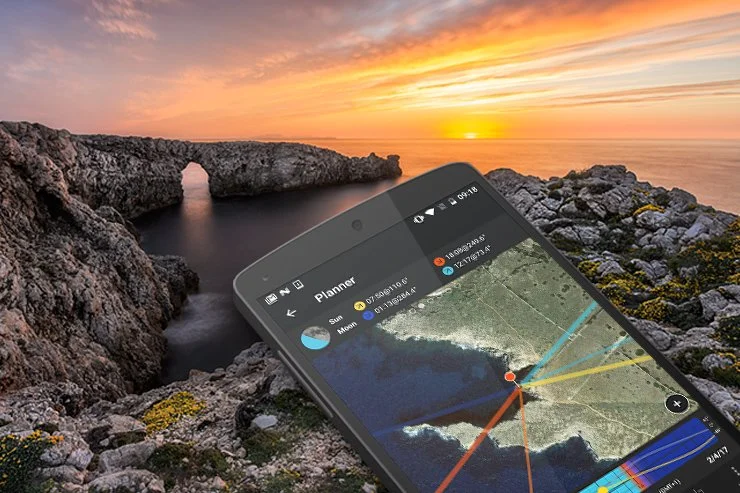 A smartphone displaying a map with weather and navigation information against a sunset over a rocky coastal landscape with an arch-shaped rock formation.