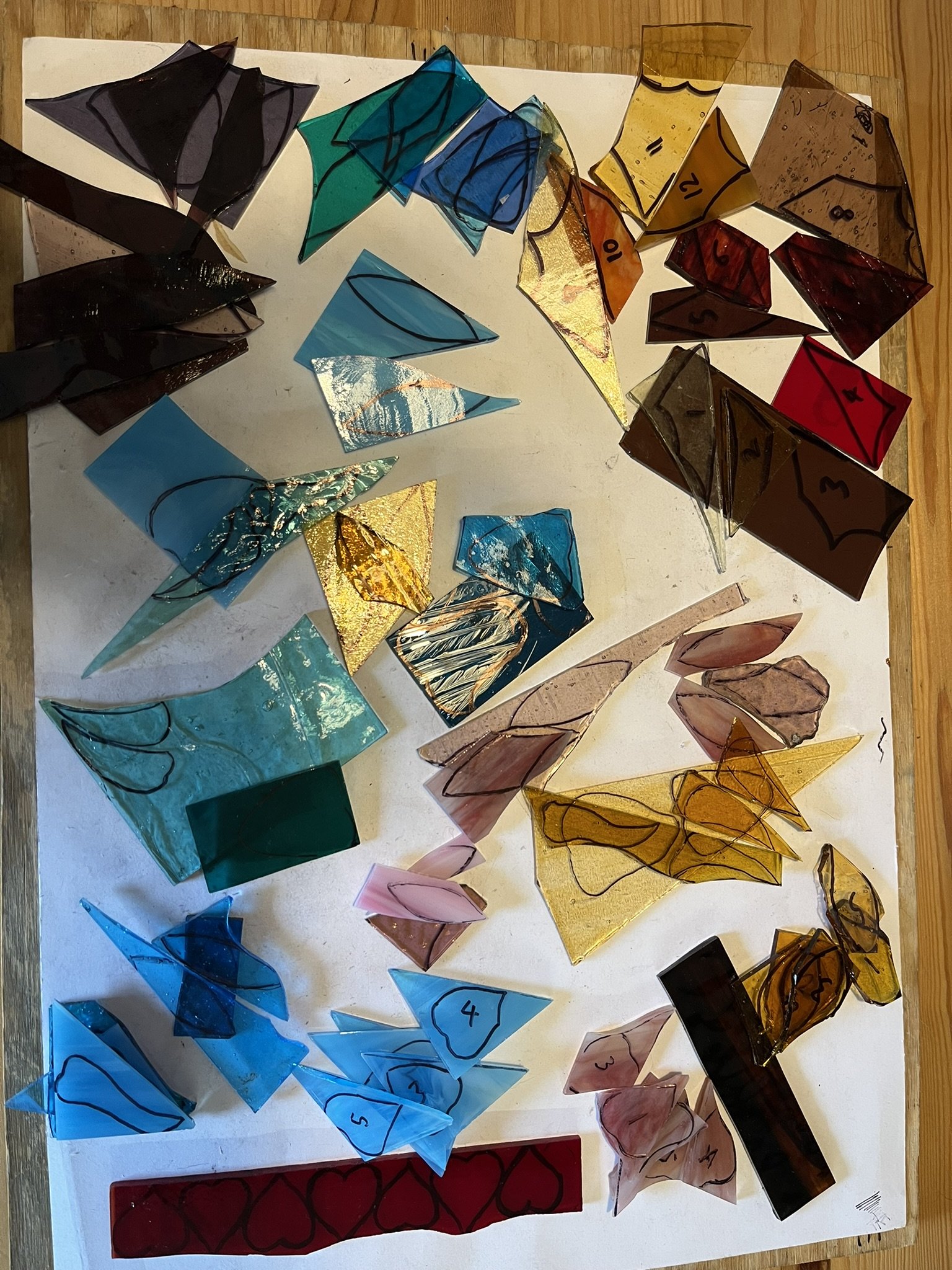 Stained glass pieces, patterns drawn on and pieces numbered, ready for cutting.