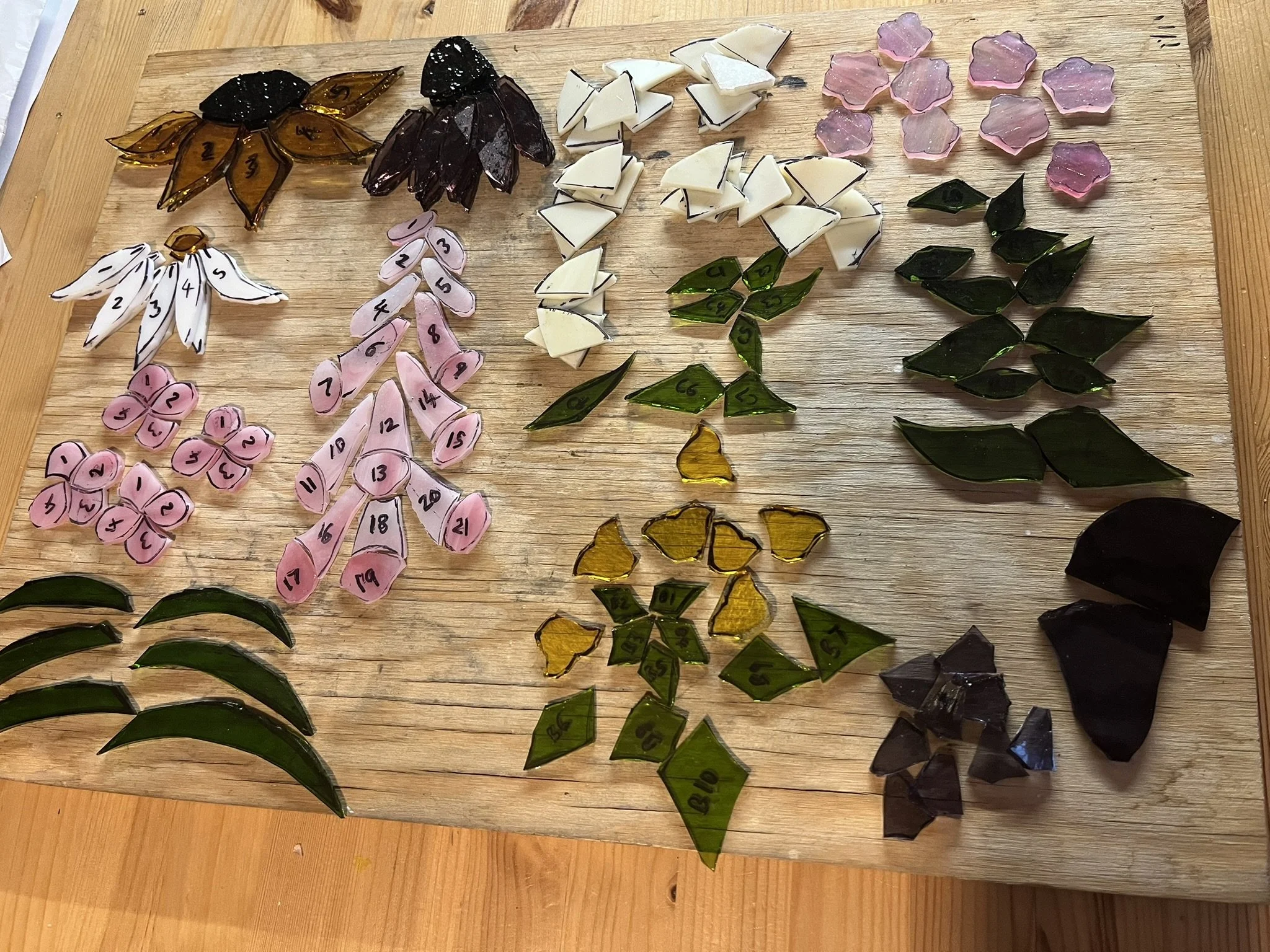 Stained glass wildflower pieces cut and ready for foiling