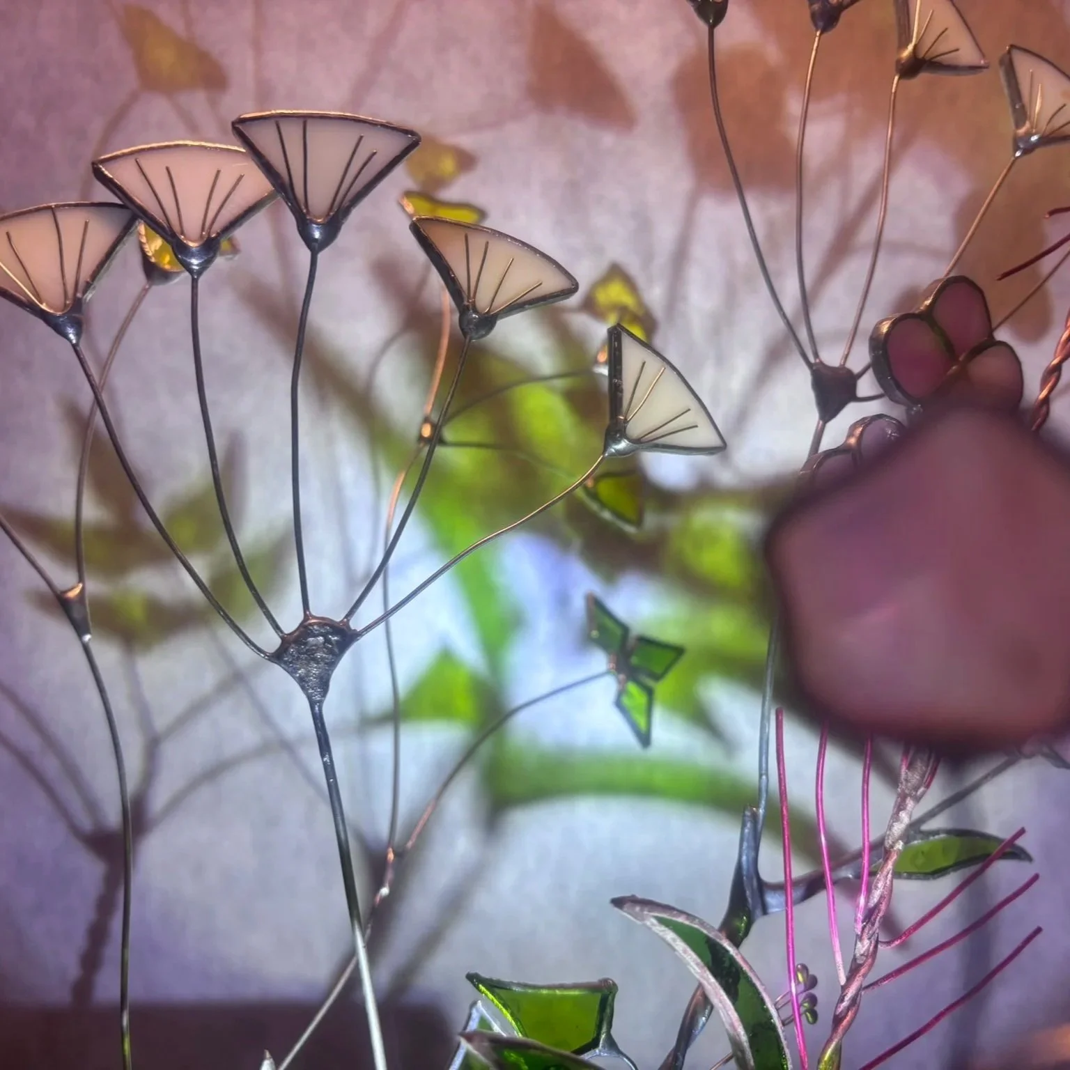 A close-up of decorative metal and stained glass flowers, featuring flower-shaped designs with thin metal stems and colored glass petals.