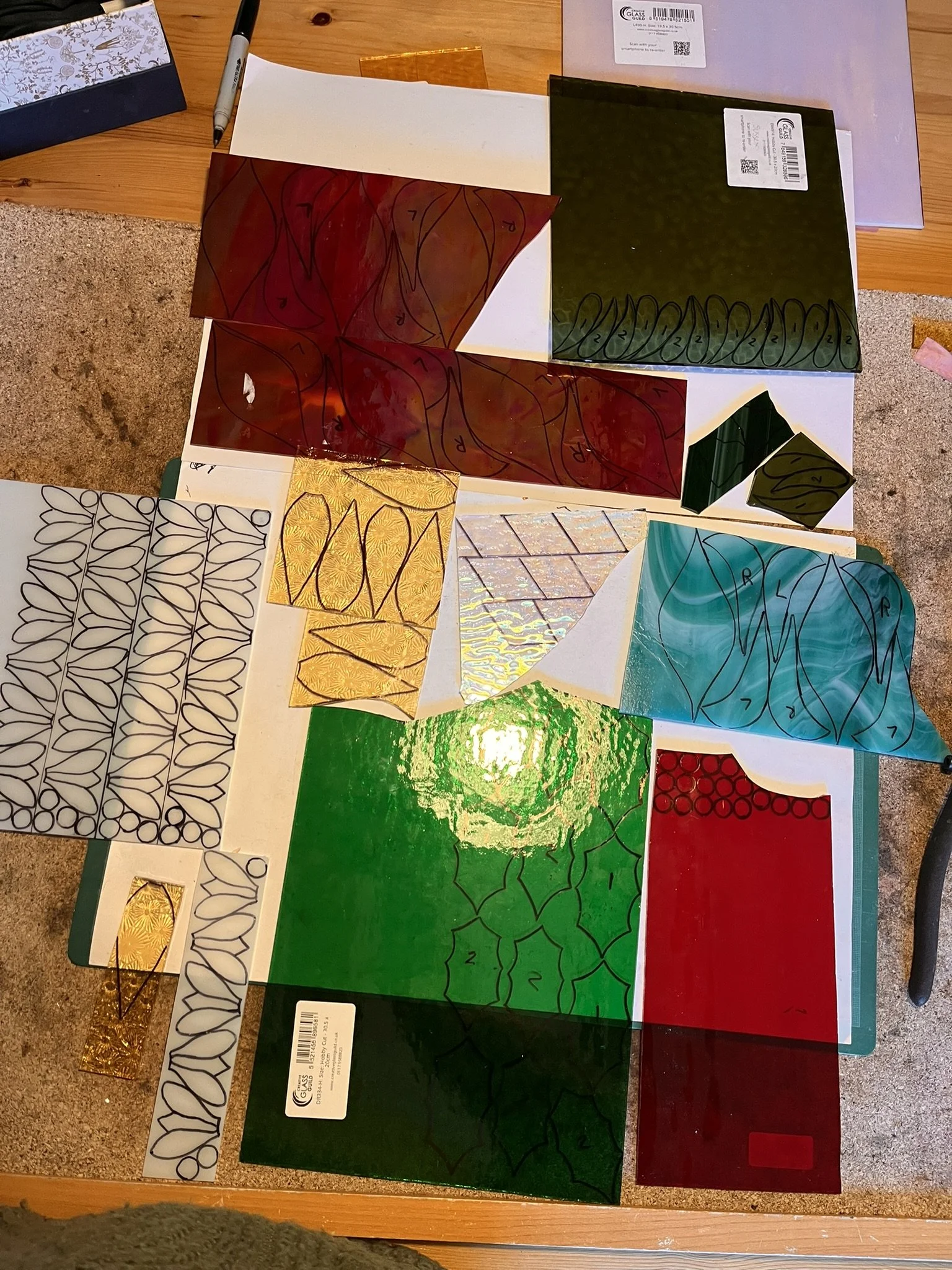 Flower patterns drawn out on stained glass sheets.