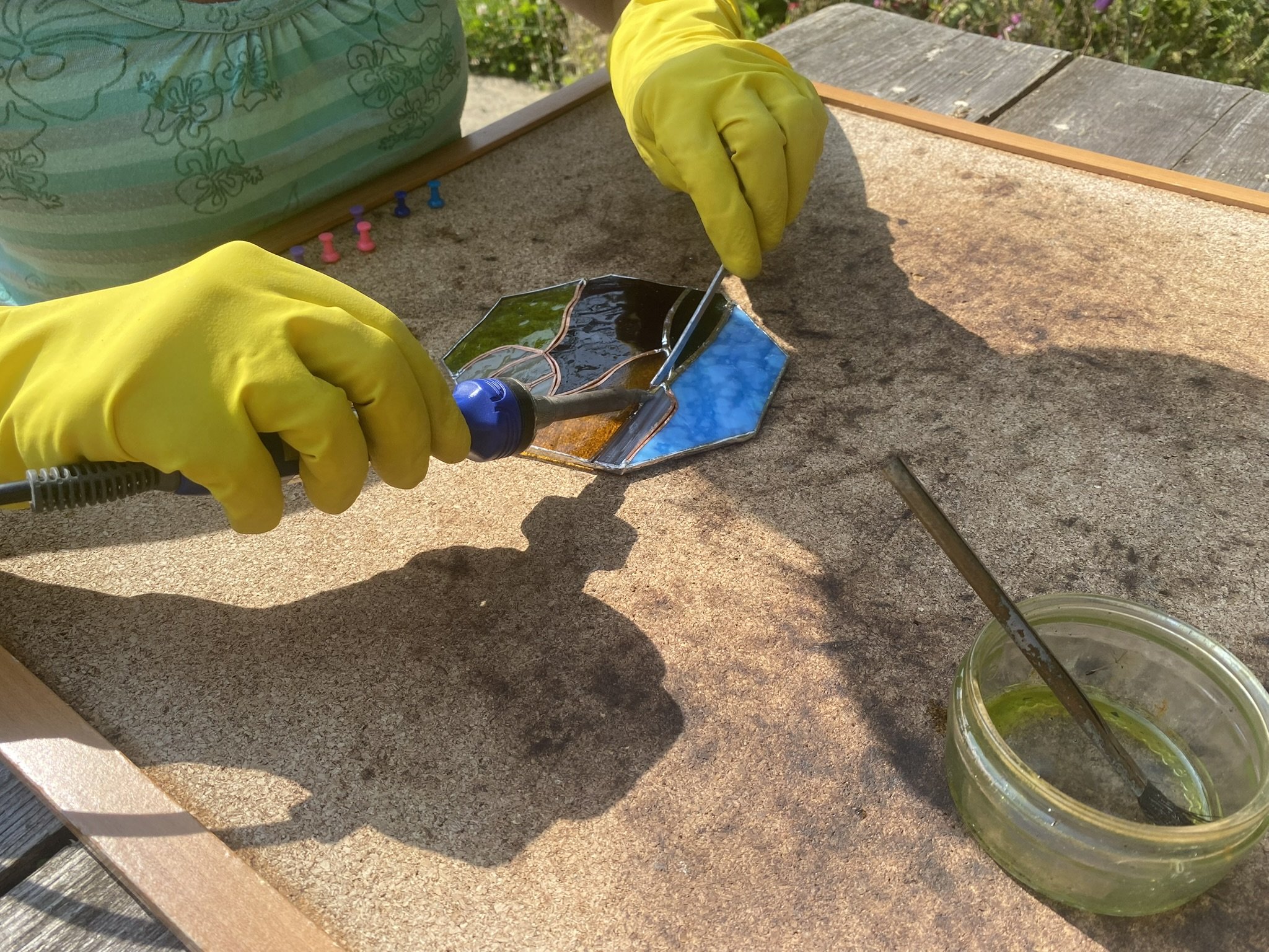 Close-up of me soldering one of my stained glass landscapes on my outdoor worktable in the garden.