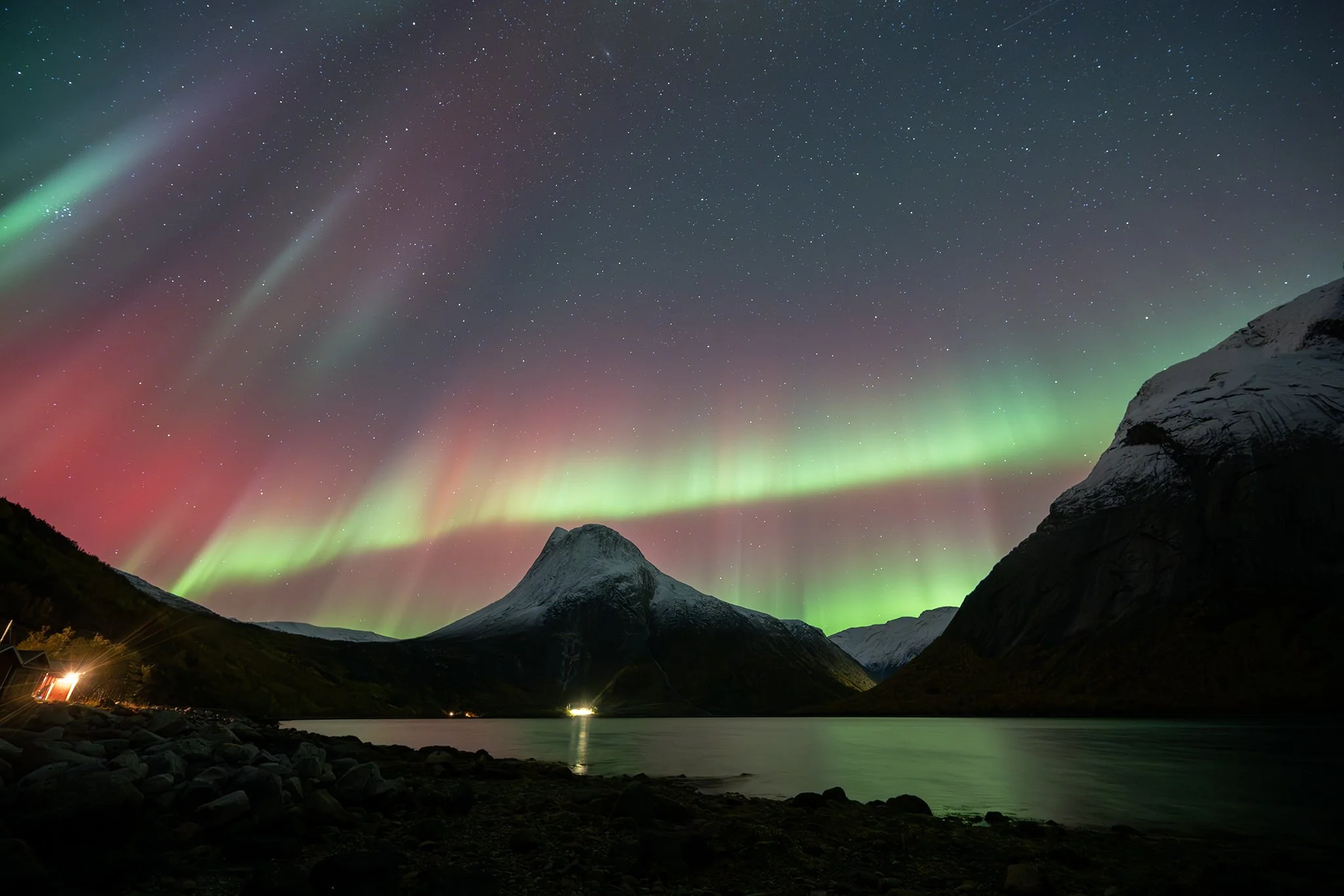 Night sky illuminated by the Northern Lights over mountains and a lake