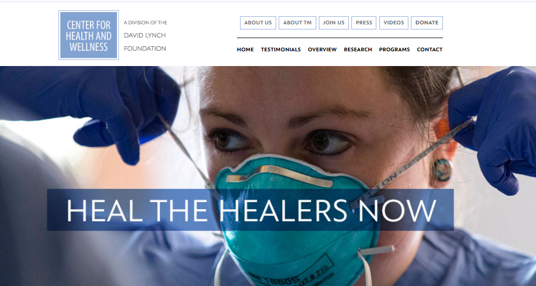 Close-up of a healthcare worker wearing a mask and gloves, adjusting her protective gear, with the phrase 'Heal the healers now' overlayed.