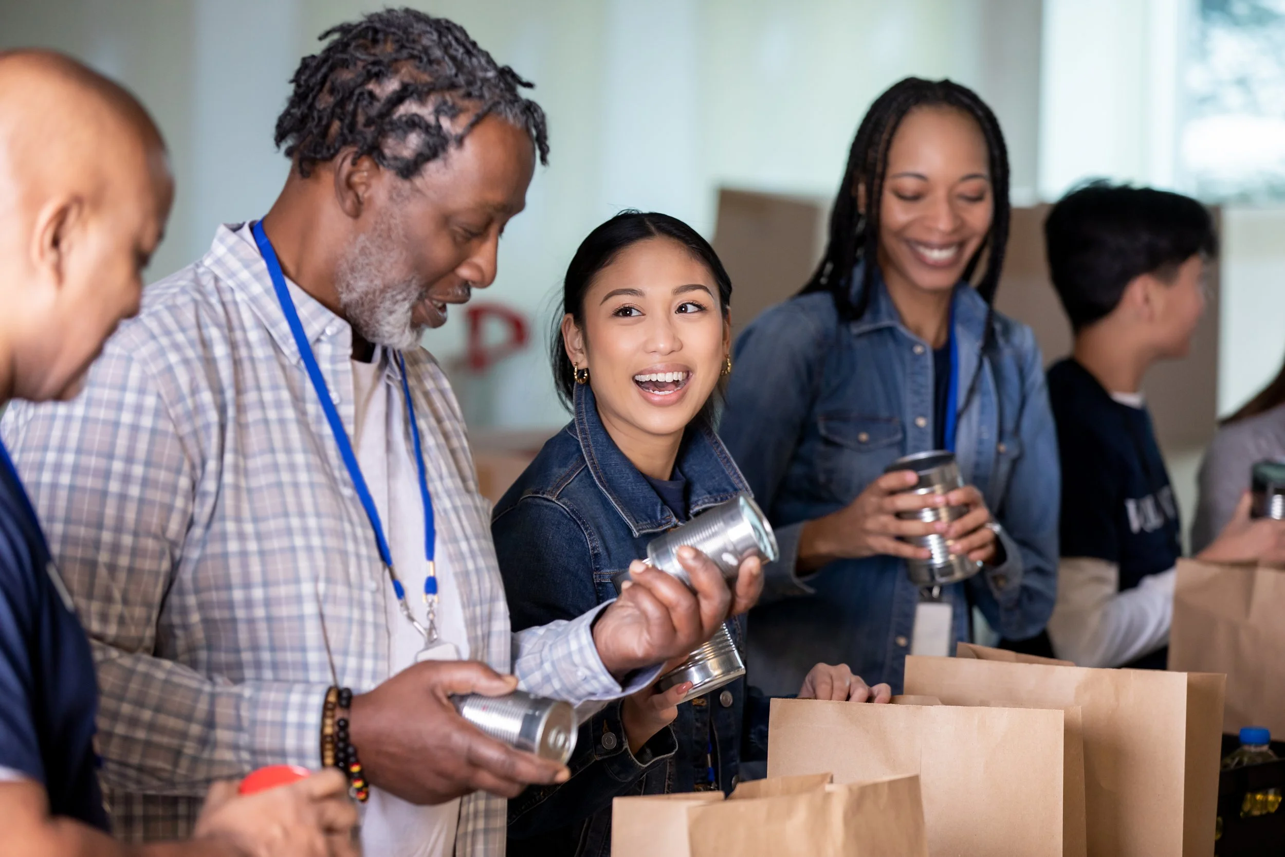 A diverse group of people packing food into paper bags at a community event.