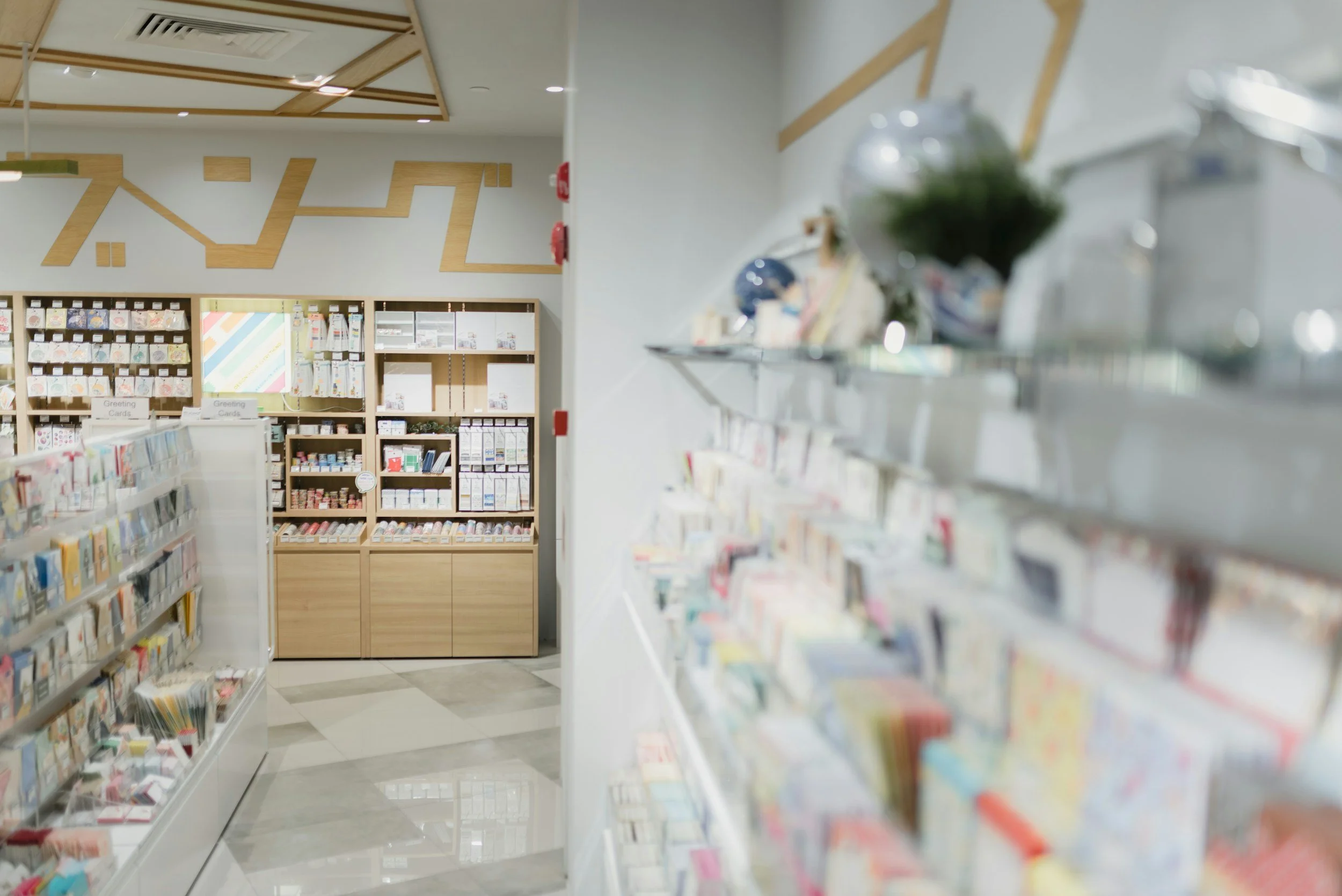 Store interior with greeting cards displayed on shelves and a wooden cabinet at the back, with ceiling decorated with wooden geometric patterns.