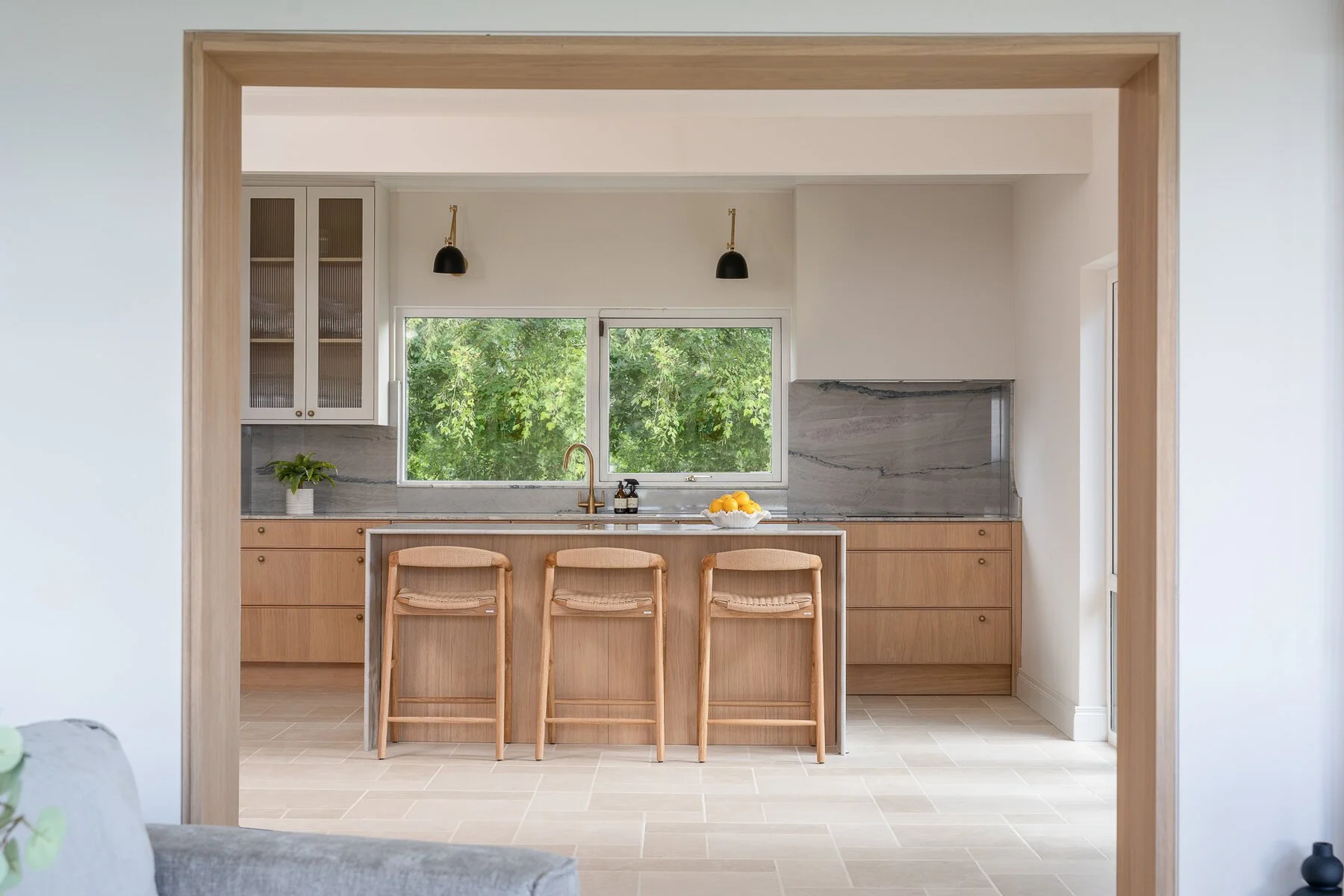 Natural oak kitchen and island viewed through a framed opening.