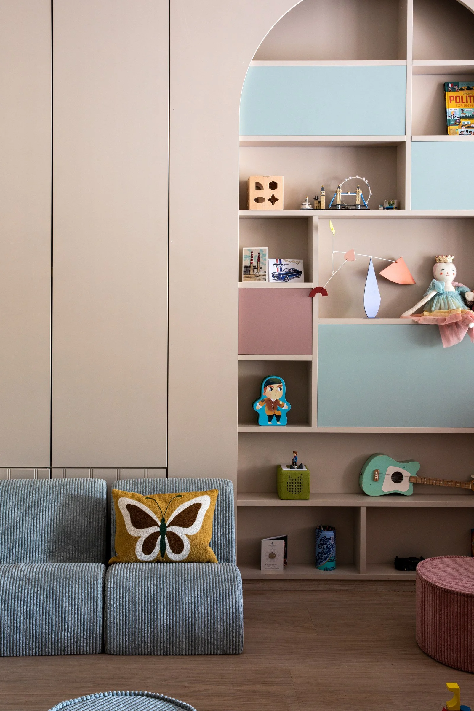Bespoke children's storage wall with wardrobes, display shelving and playful colour.
