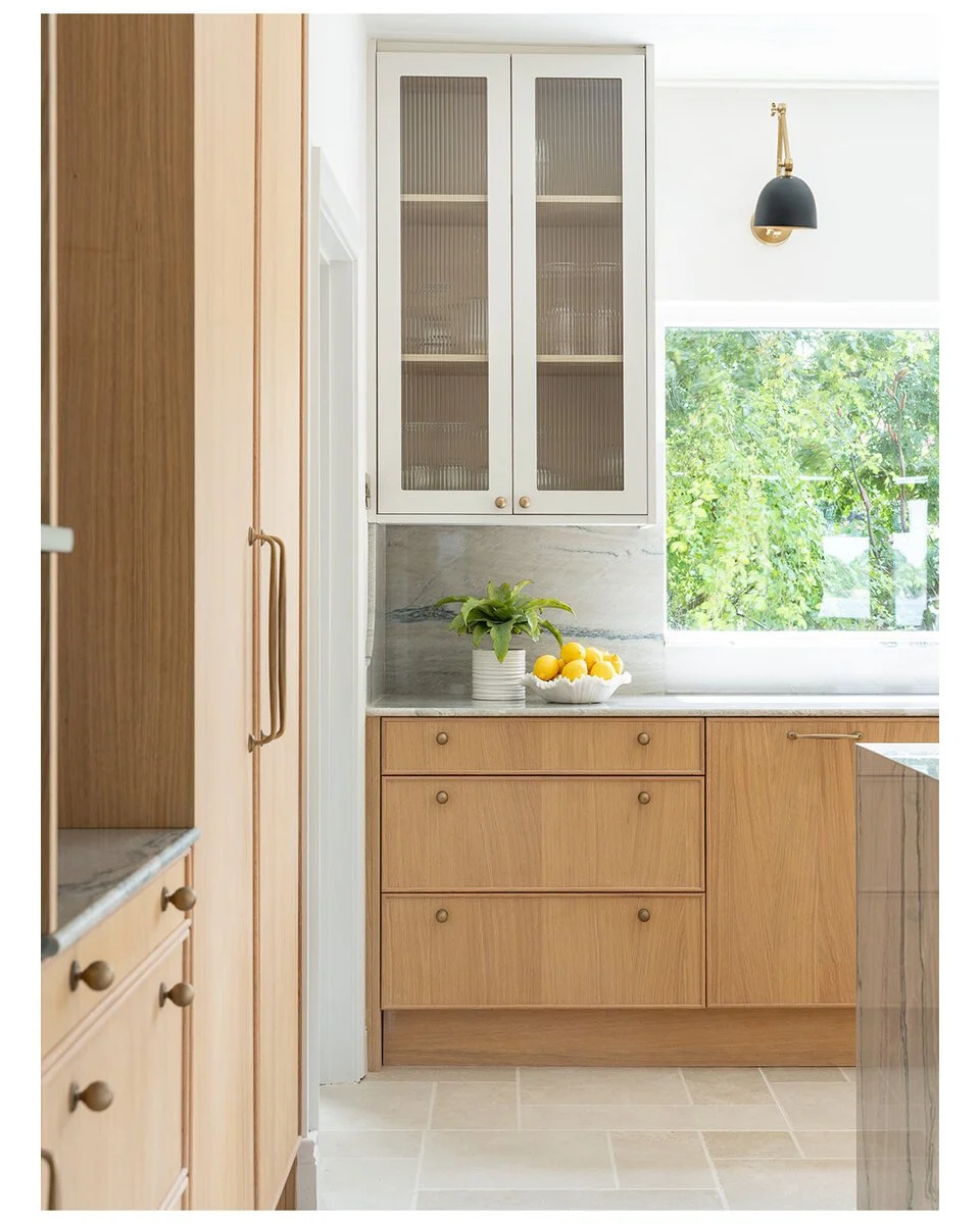 Natural oak drawers with brass hardware, fluted glass cabinet and stone splashback.