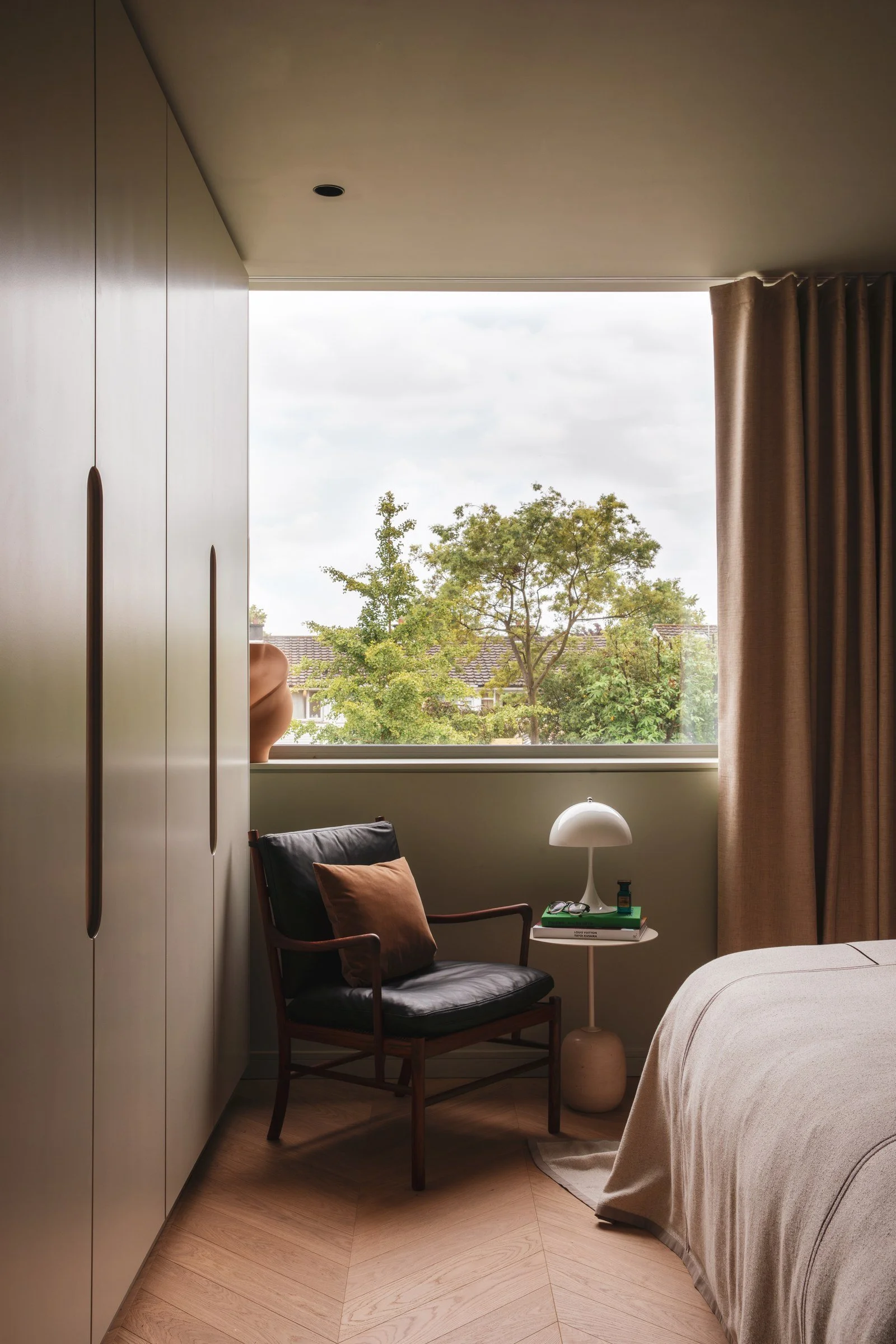 Quiet reading nook with fitted cabinetry, an armchair and garden views.