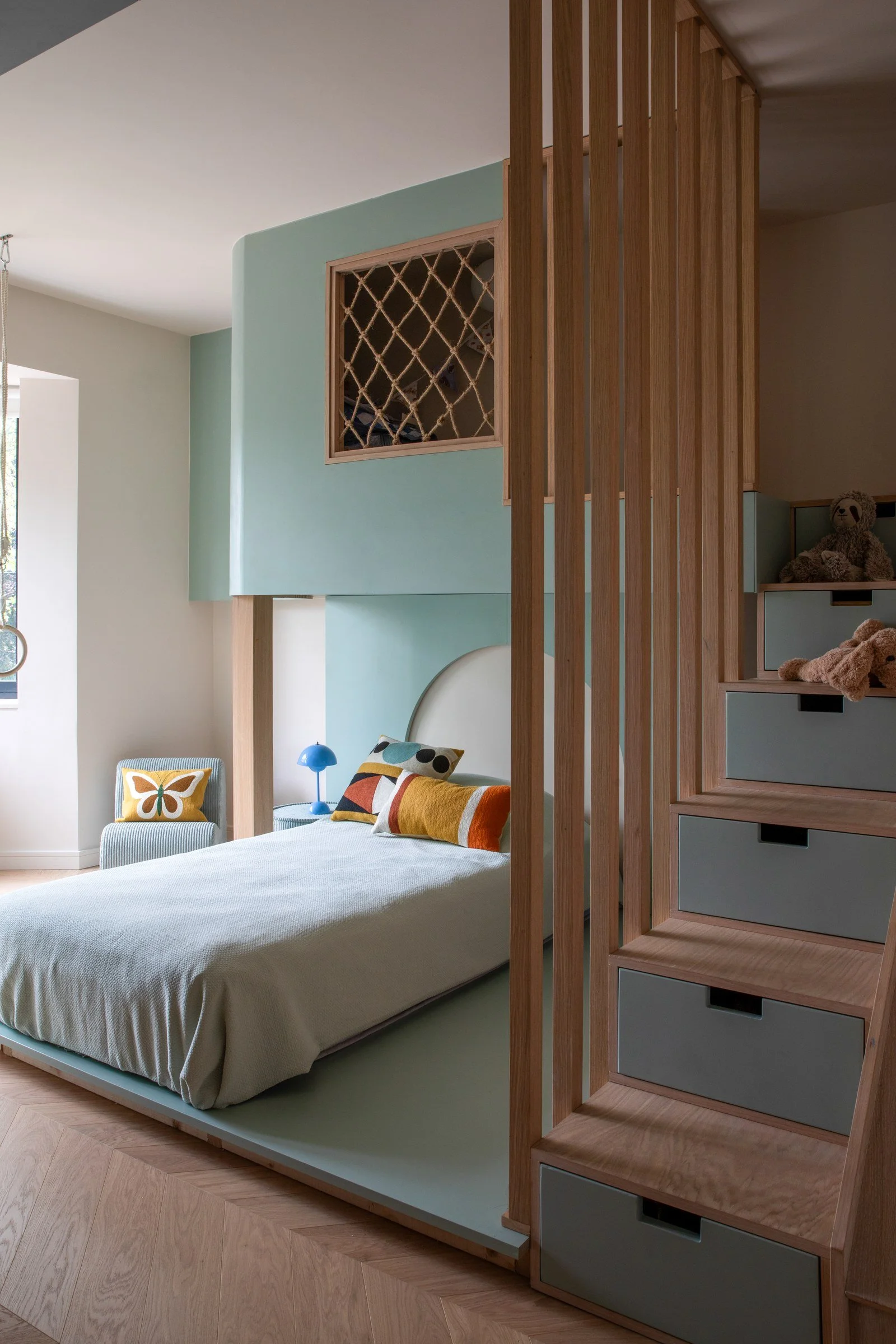 Children's bedroom with a raised bed, timber slatted screen and storage steps.
