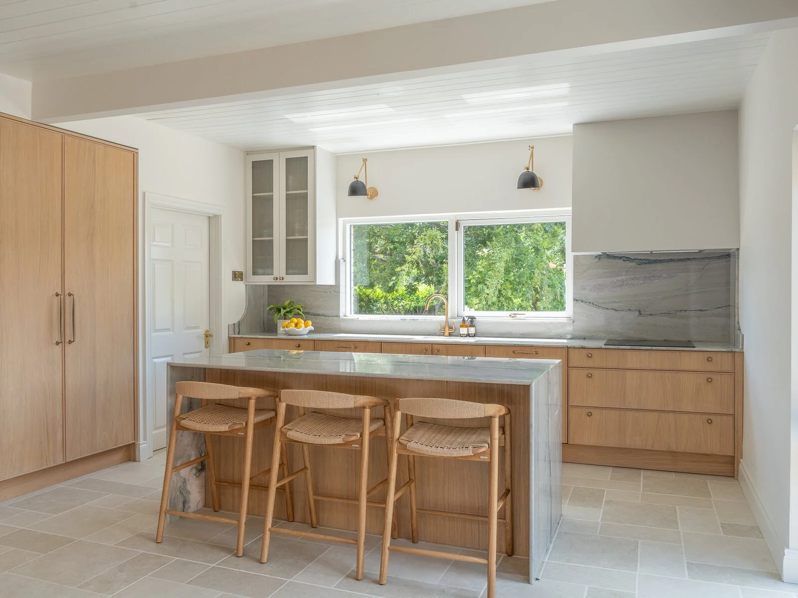 Natural oak kitchen with island, pantry cabinetry and integrated seating by Royal & Co.