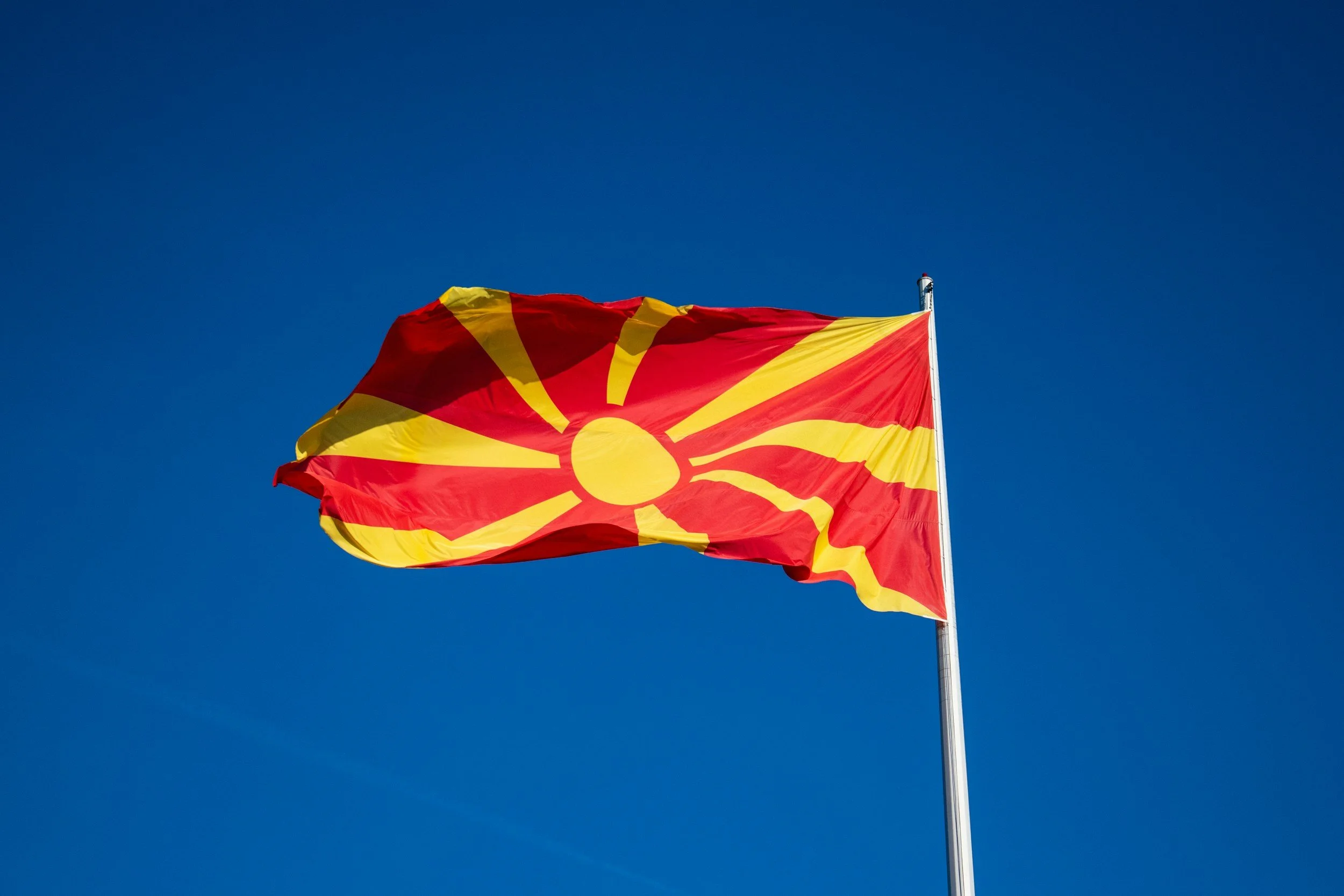 North Macedonia flag flying against a clear blue sky.
