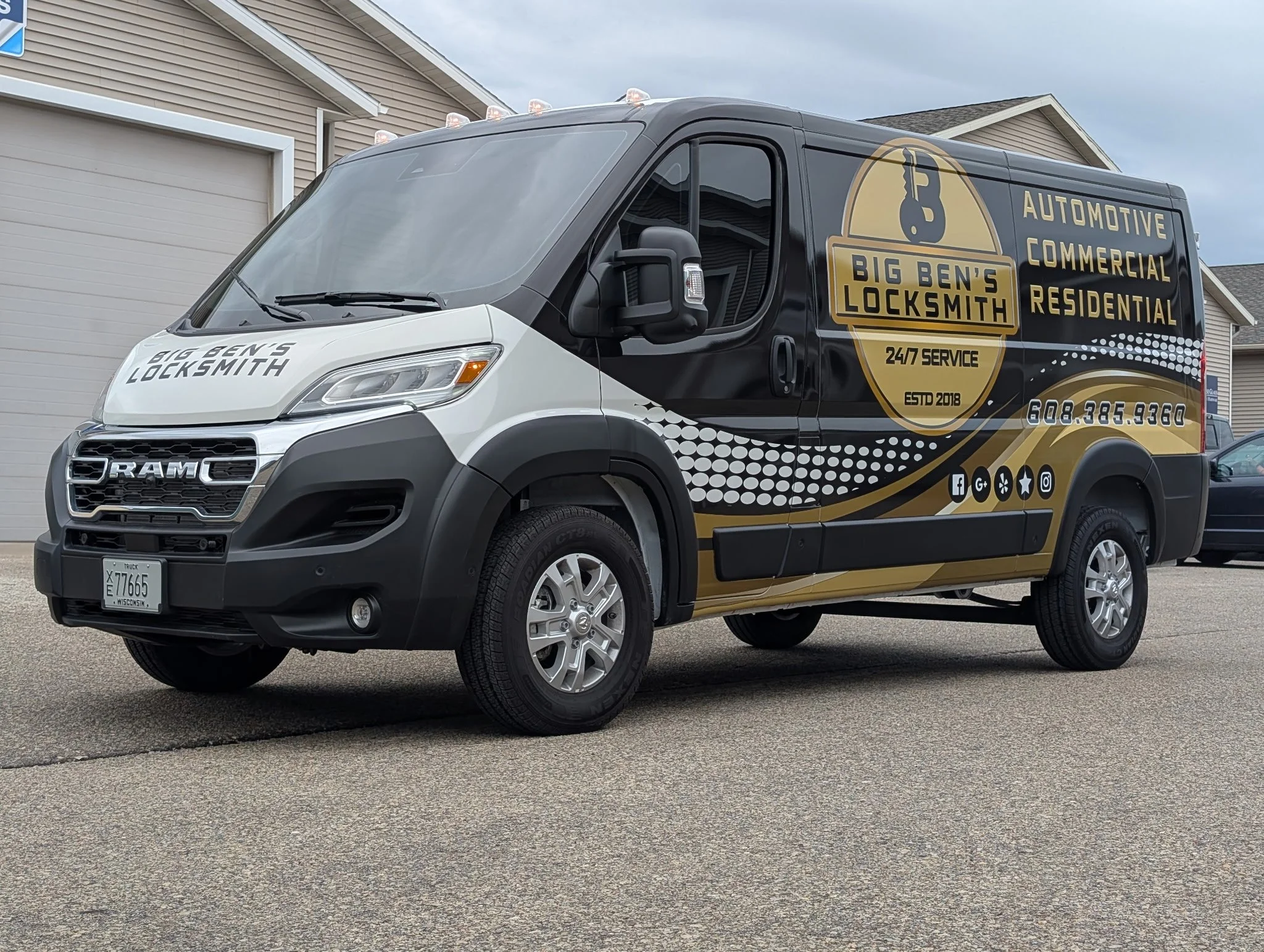 A black and white locksmith service truck with gold and black graphics and text, parked on a driveway.