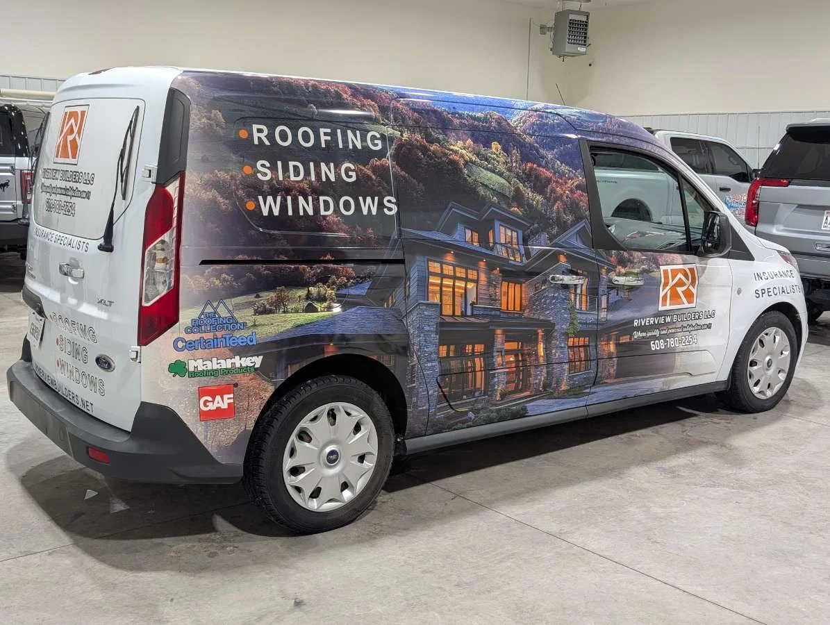 Company van advertising roofing, siding, and window services with a large house and mountain landscape graphic.
