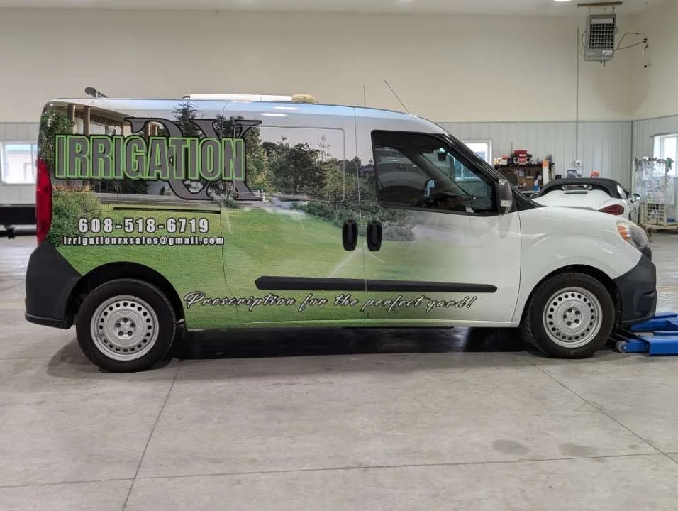 Side view of a van with an advertisement for irrigation services, displaying a green lawn, trees, and the company's contact information on the side.