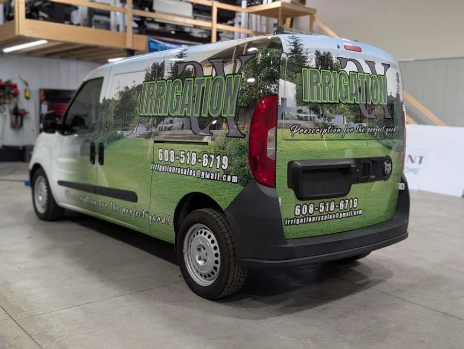 A company van for irrigation services with a green and black design. The van displays the word 'IRRIGATION' in large green letters, contact details, and the slogan 'Complete up to the perfect yard!'.