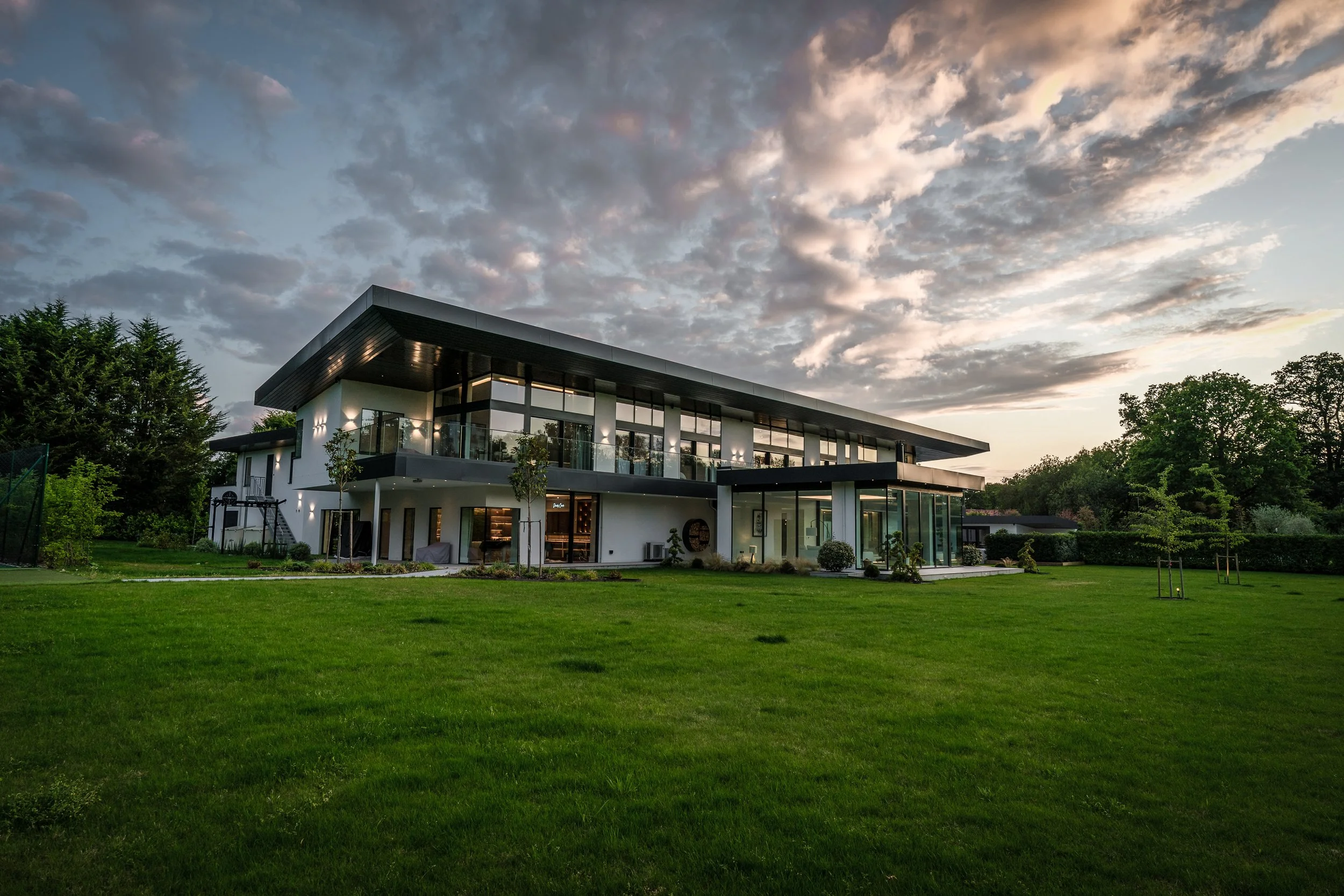 Completed large contemporary dwelling with a monopitch roof, overlooking the rear garden, featuring a single-storey glass pavilion projection, designed by Tony Holt Design, a CIAT-registered architectural practice.