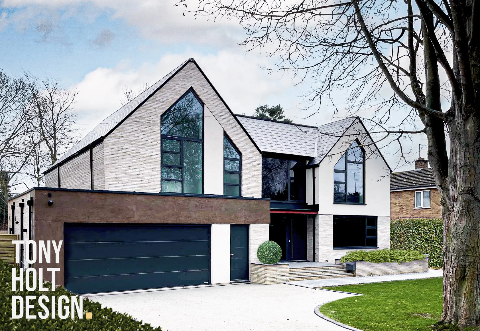 Modern two-storey house with large glass windows, integrated garage, and landscaped front garden with trees and steps leading to the entrance, designed by Tony Holt Design, a CIAT-registered architectural practice.