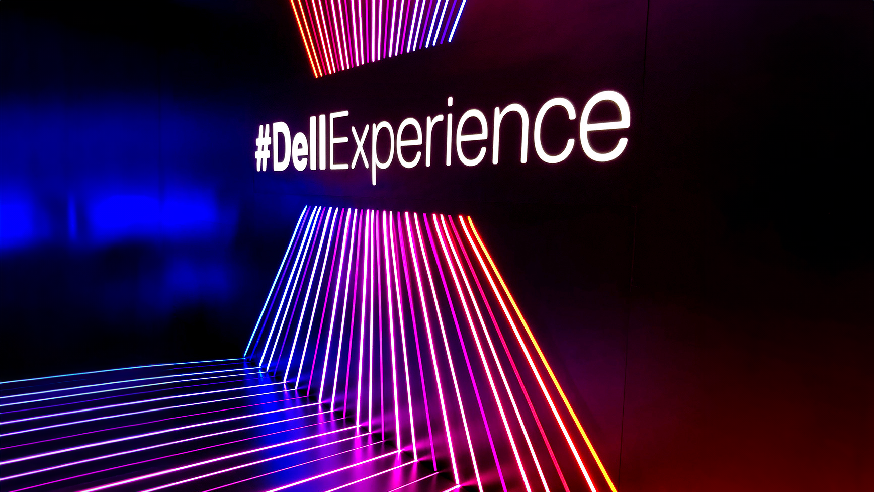 Neon lights displaying the hashtag #DellExperience, with colorful light lines on a dark background.