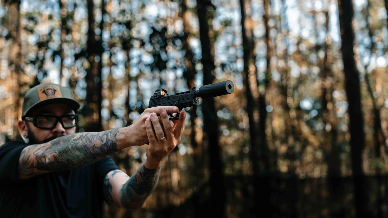 Suppressed pistol resting on a pine log