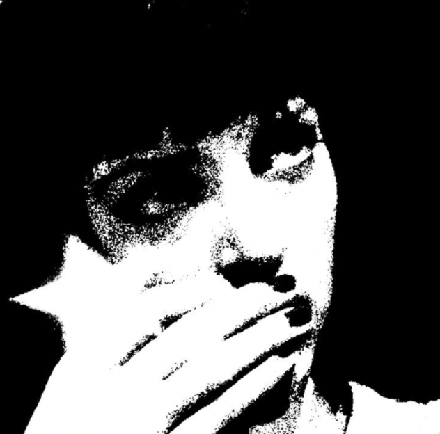 Black and white stylized portrait of a young person with glasses, partially covering their face with their hand.