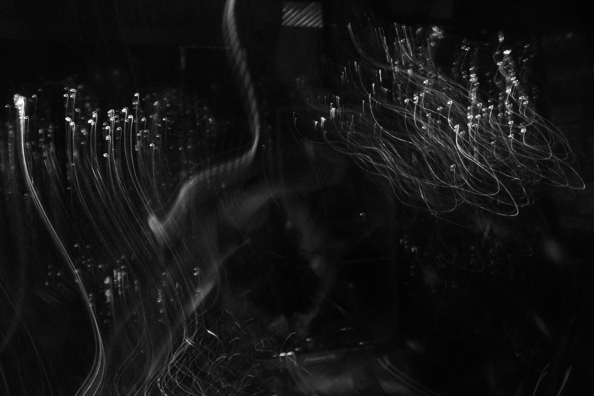 Abstract black and white photo of light trails and streaks in a dark environment.