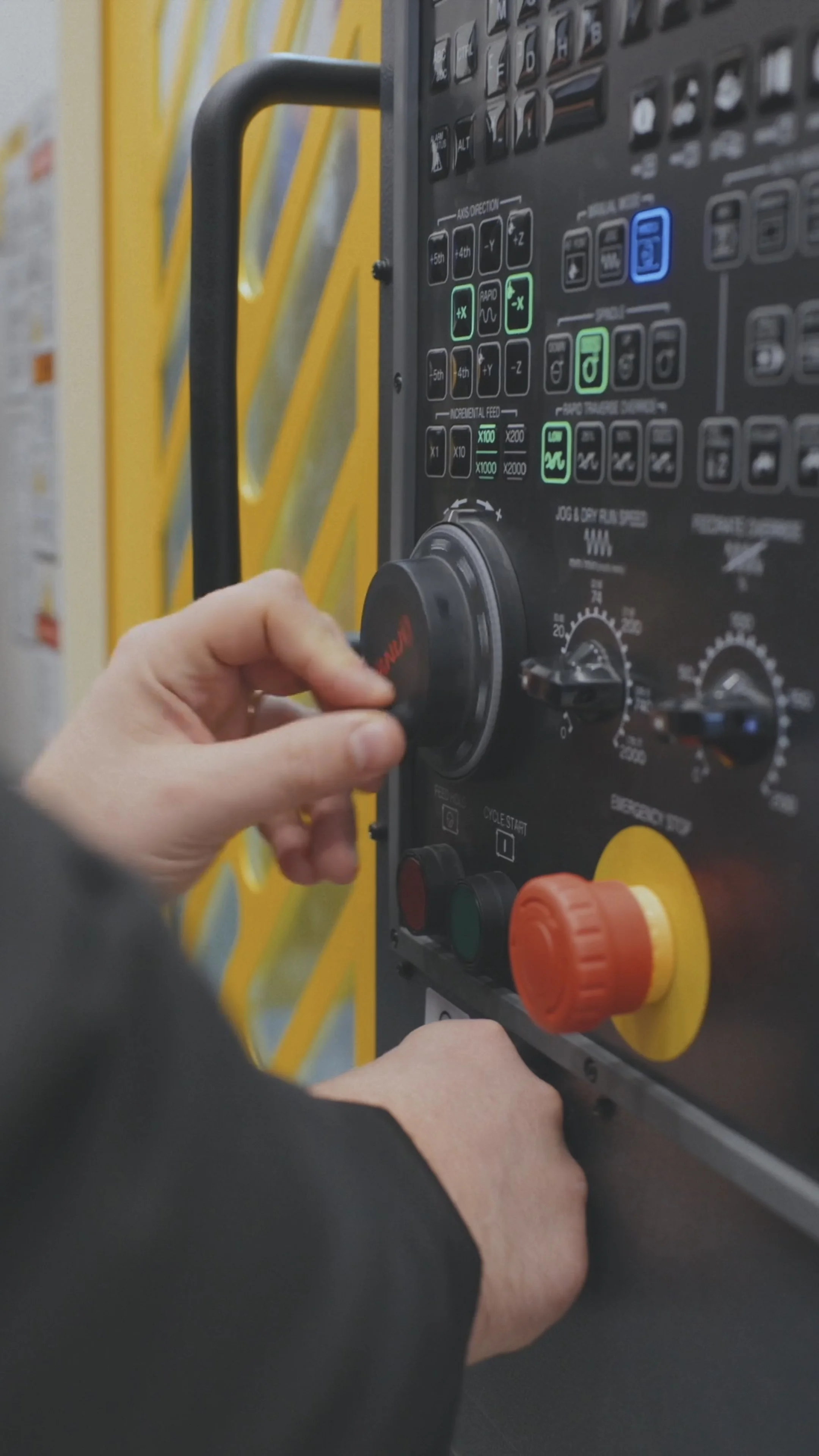Persona che regola il pannello di controllo di un macchina industriale o di sicurezza, con manopole e pulsanti colorati.