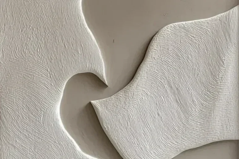 Close-up image of textured, abstract, white ceramic sculpture with flowing, rippled patterns.