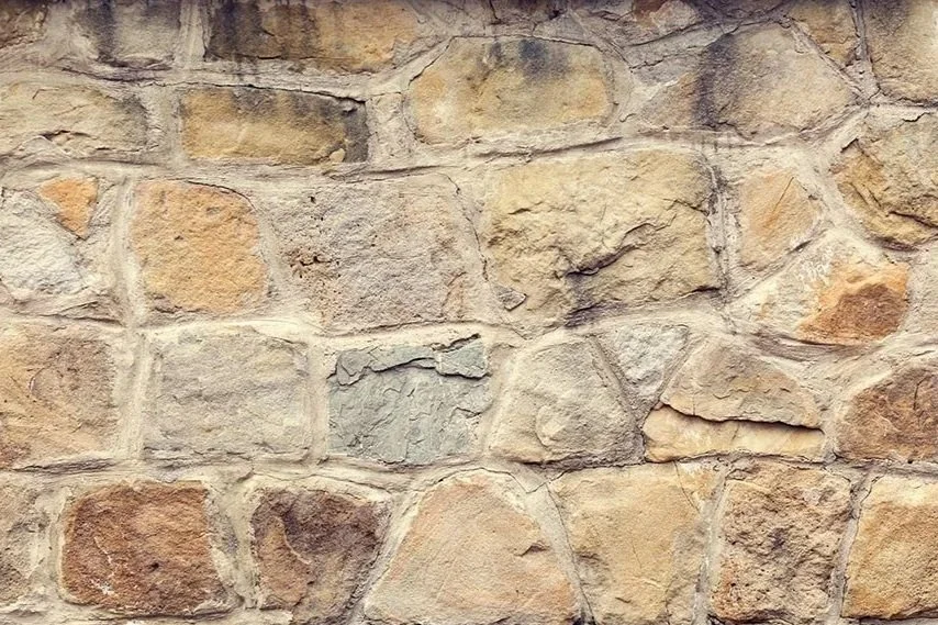 Close-up of a stone wall with irregularly shaped stones and mortar.