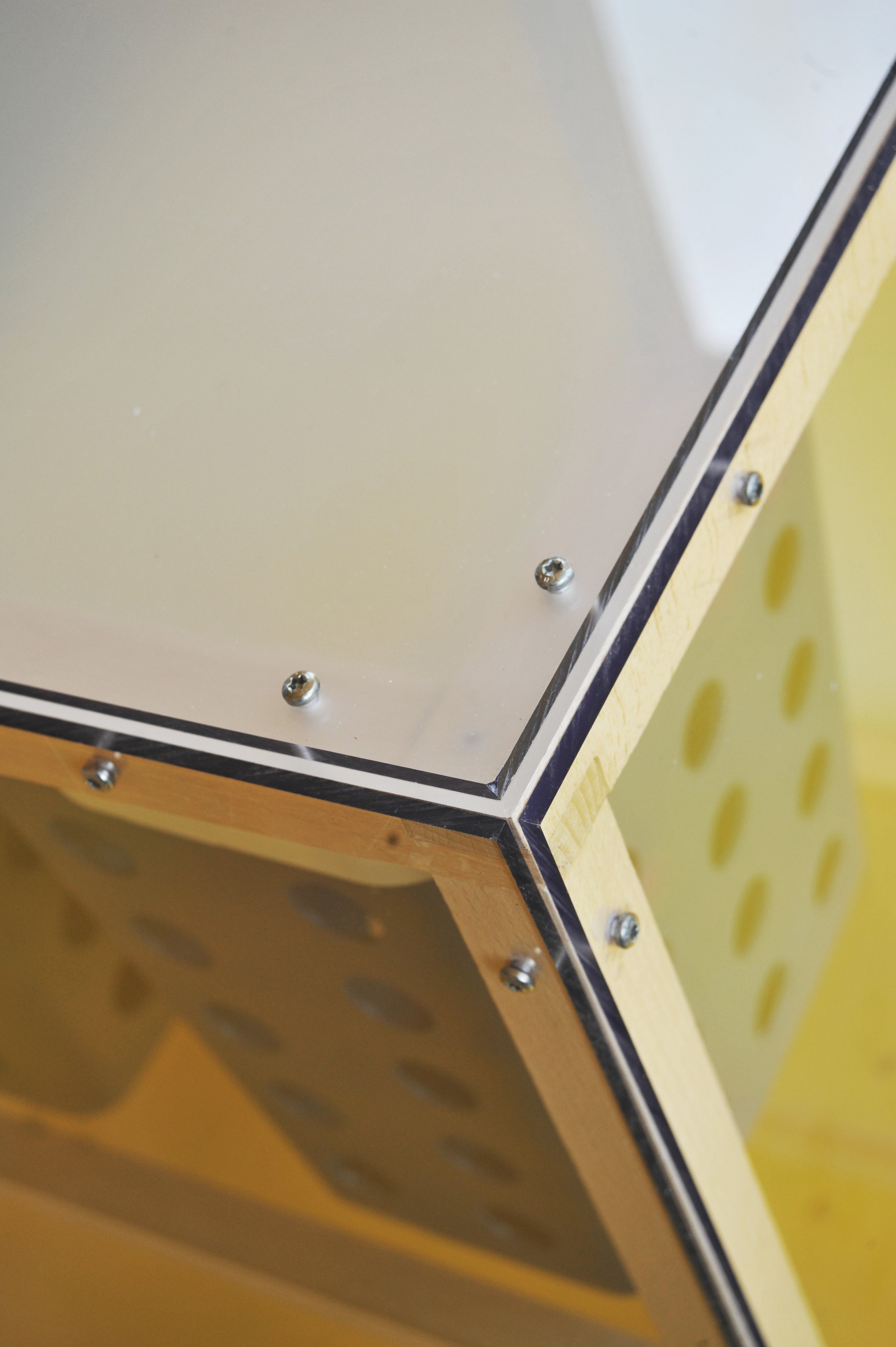 En kasse lavet af træ med metalplader og skruer, der har huller i siderne.