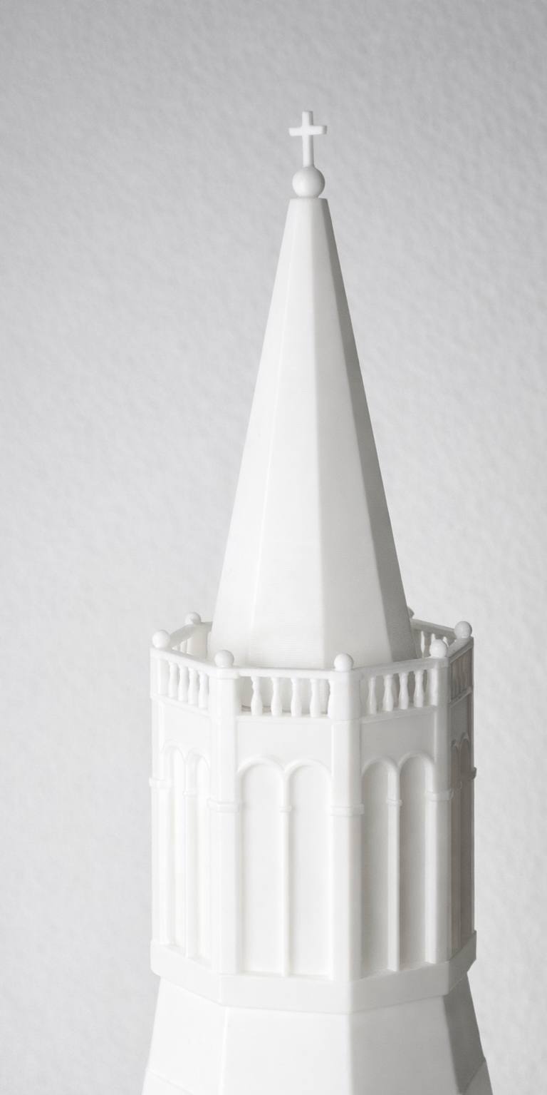 Modello di una torre bianca con una lanterna alta e una croce sulla cima, in stile architettonico gotico.
