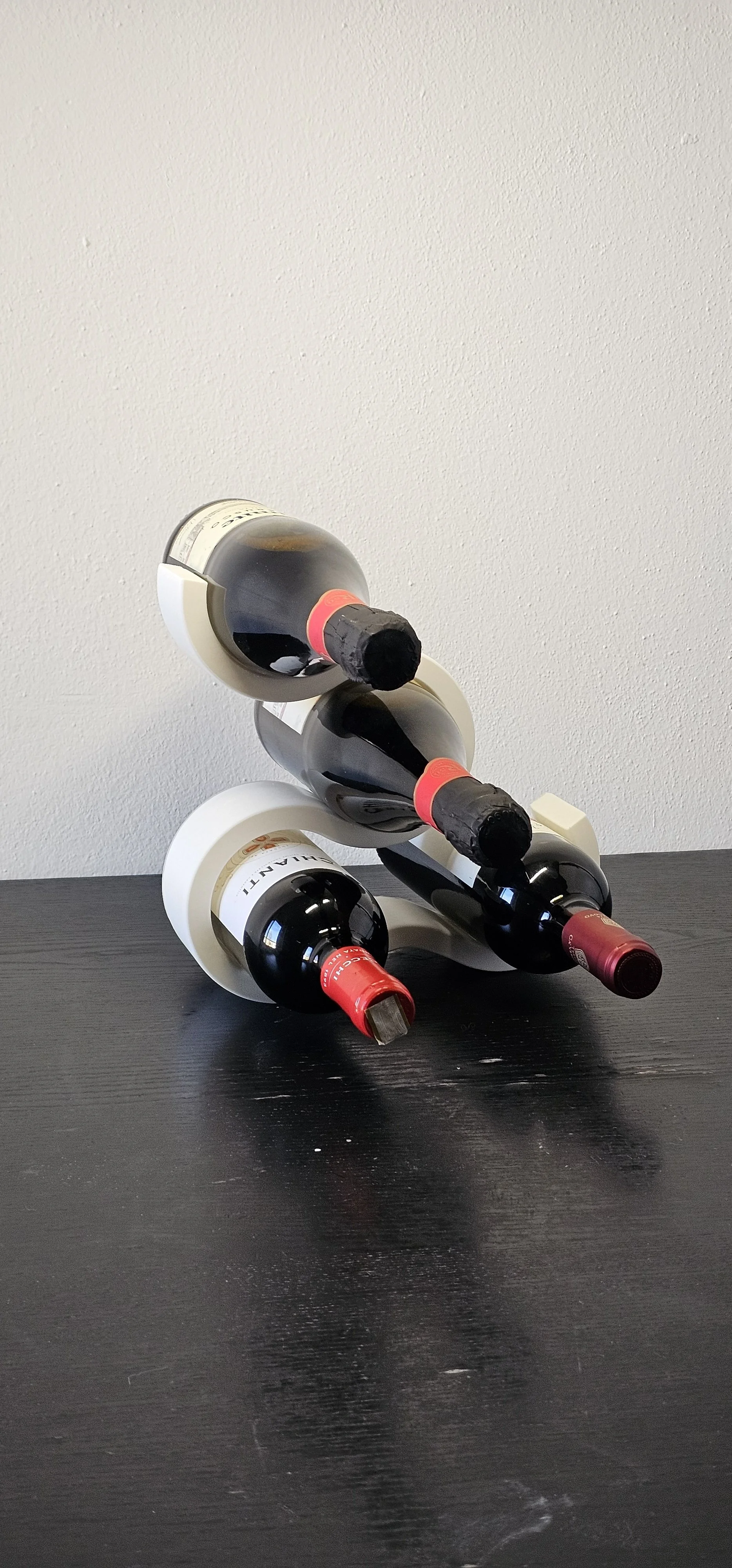 Scultura di bottiglie di vino impilate in modo artistico su un tavolo di legno, creando una figura tridimensionale