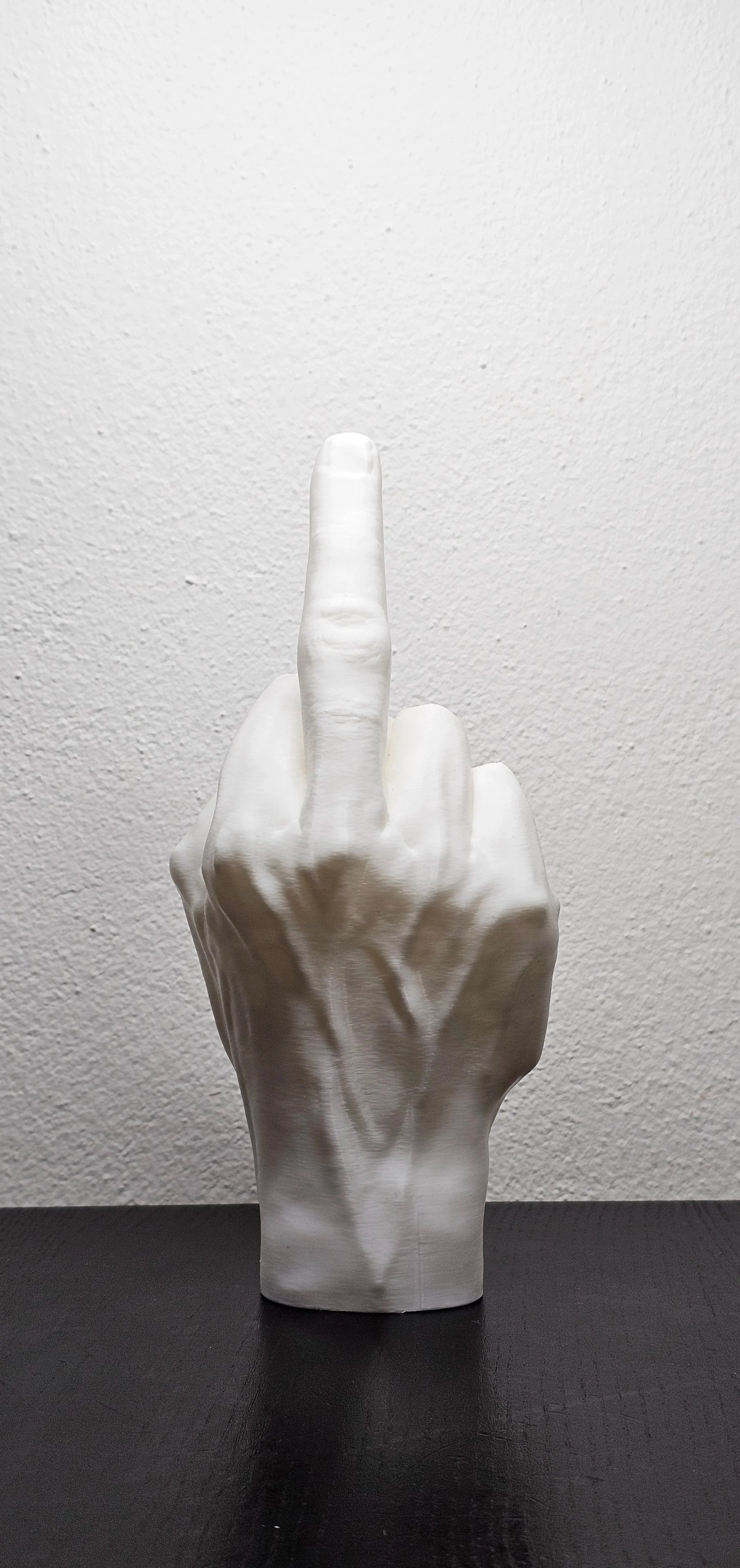 Statua di una mano bianca che mostra il dito medio alzato