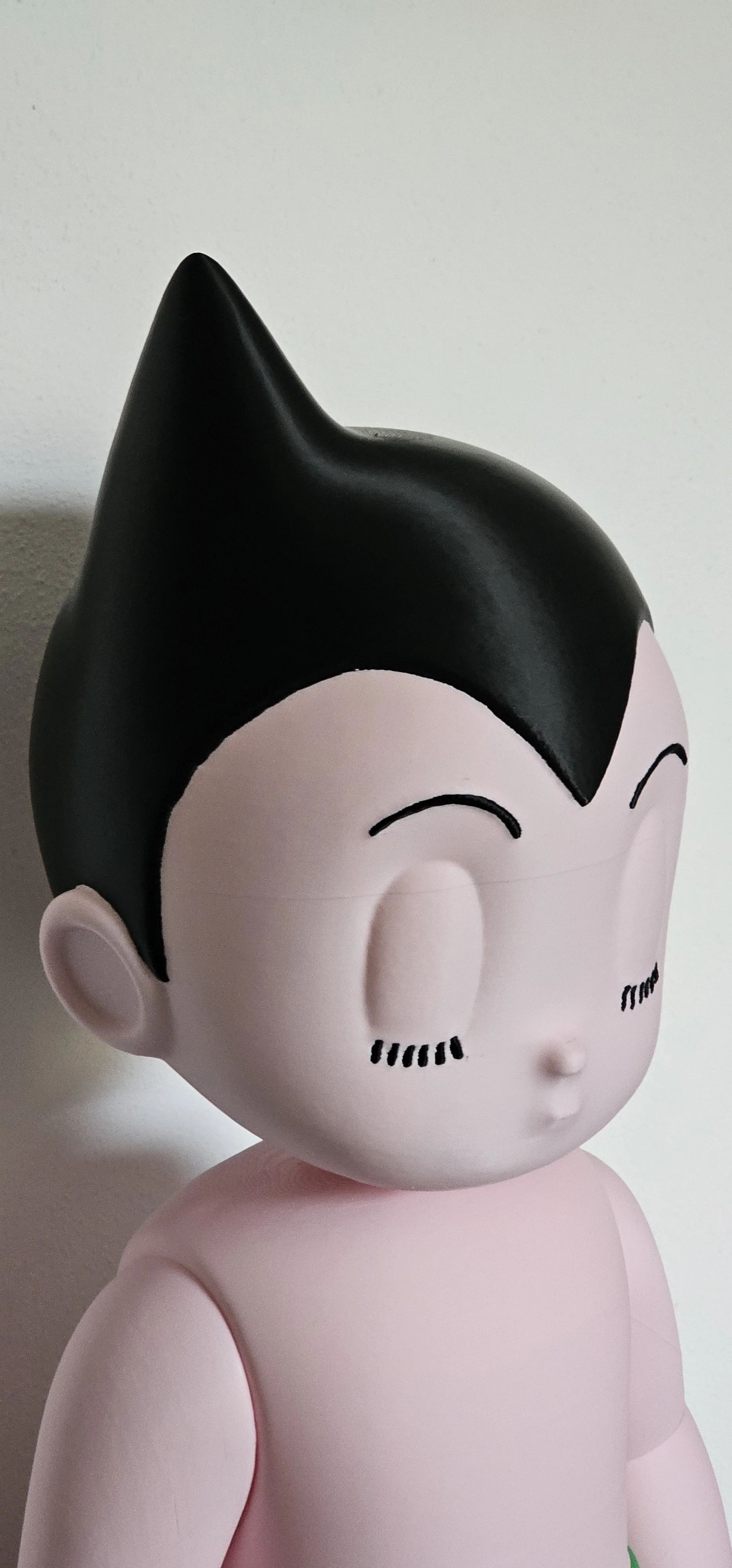 Statua di un personaggio cartoonesco, con capelli neri appuntiti, viso pallido, occhi chiusi e sorriso.