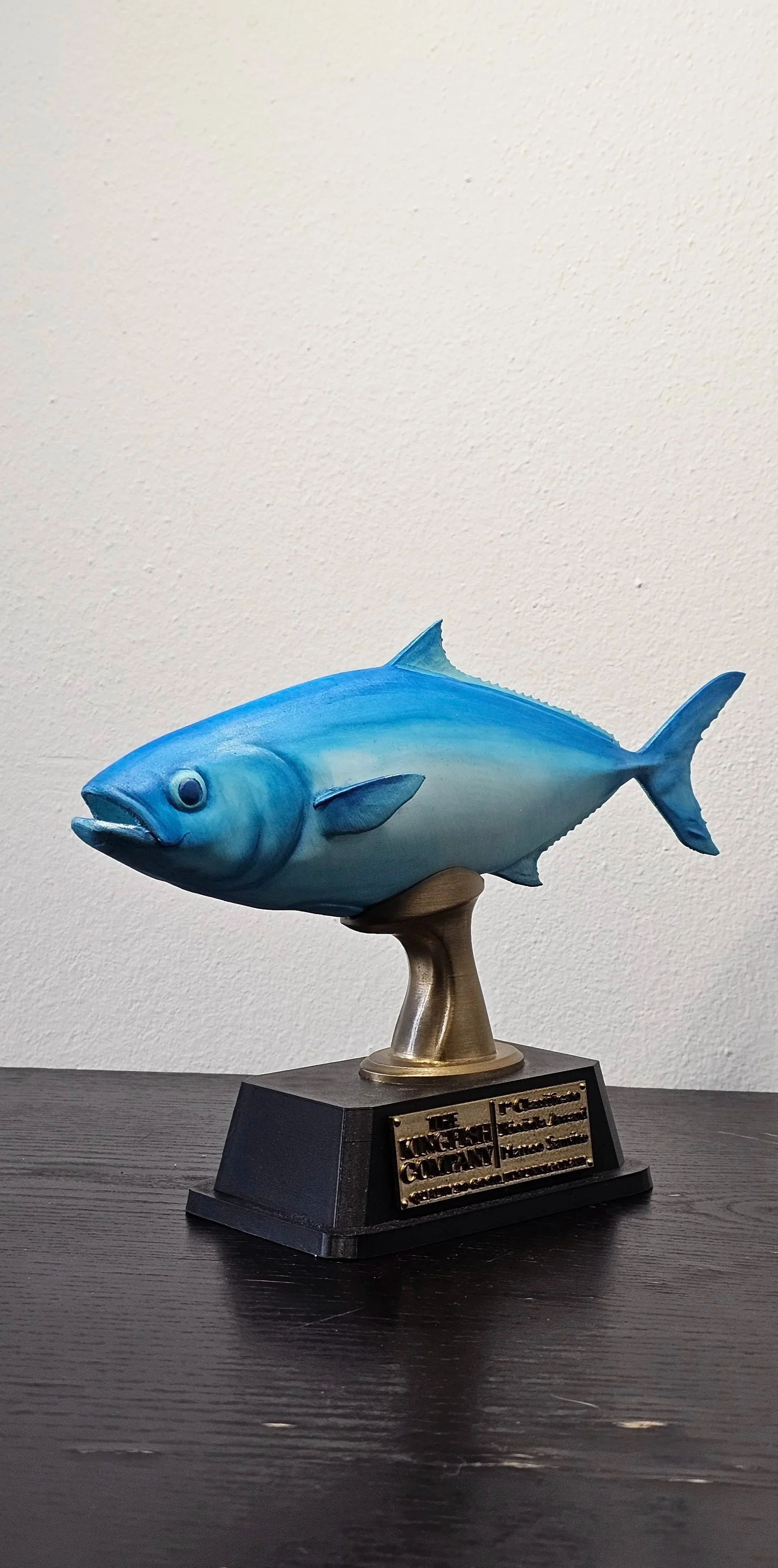 Trofeo a forma di pesce blu su base nera con iscrizione commemorativa