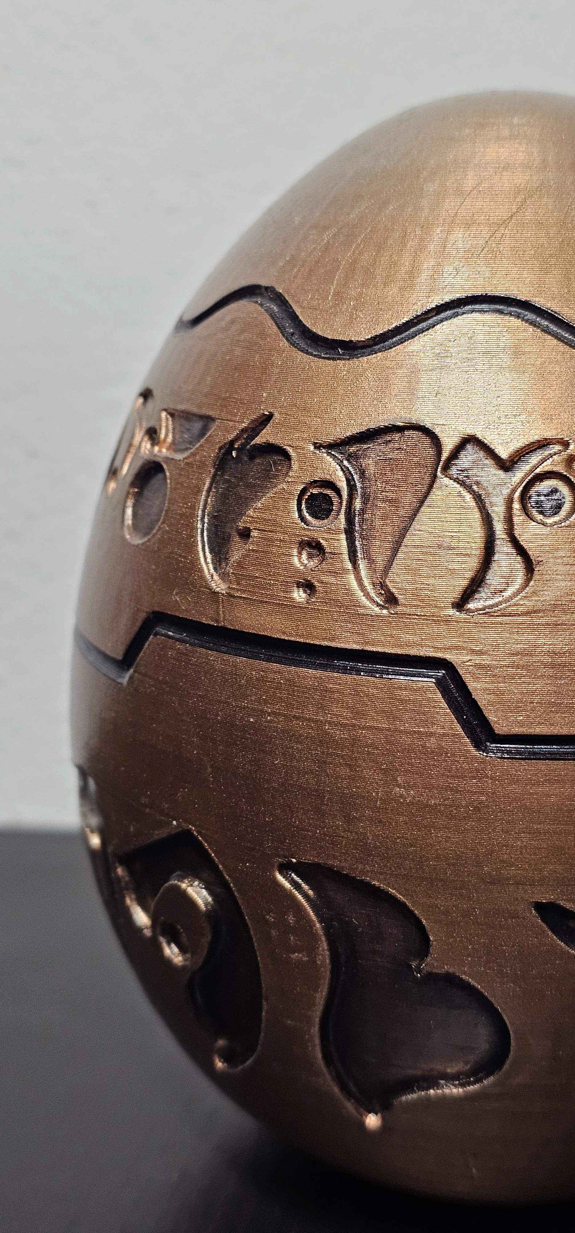 Una palla di metallo color rame con incisioni, iscrizioni e linee decorative