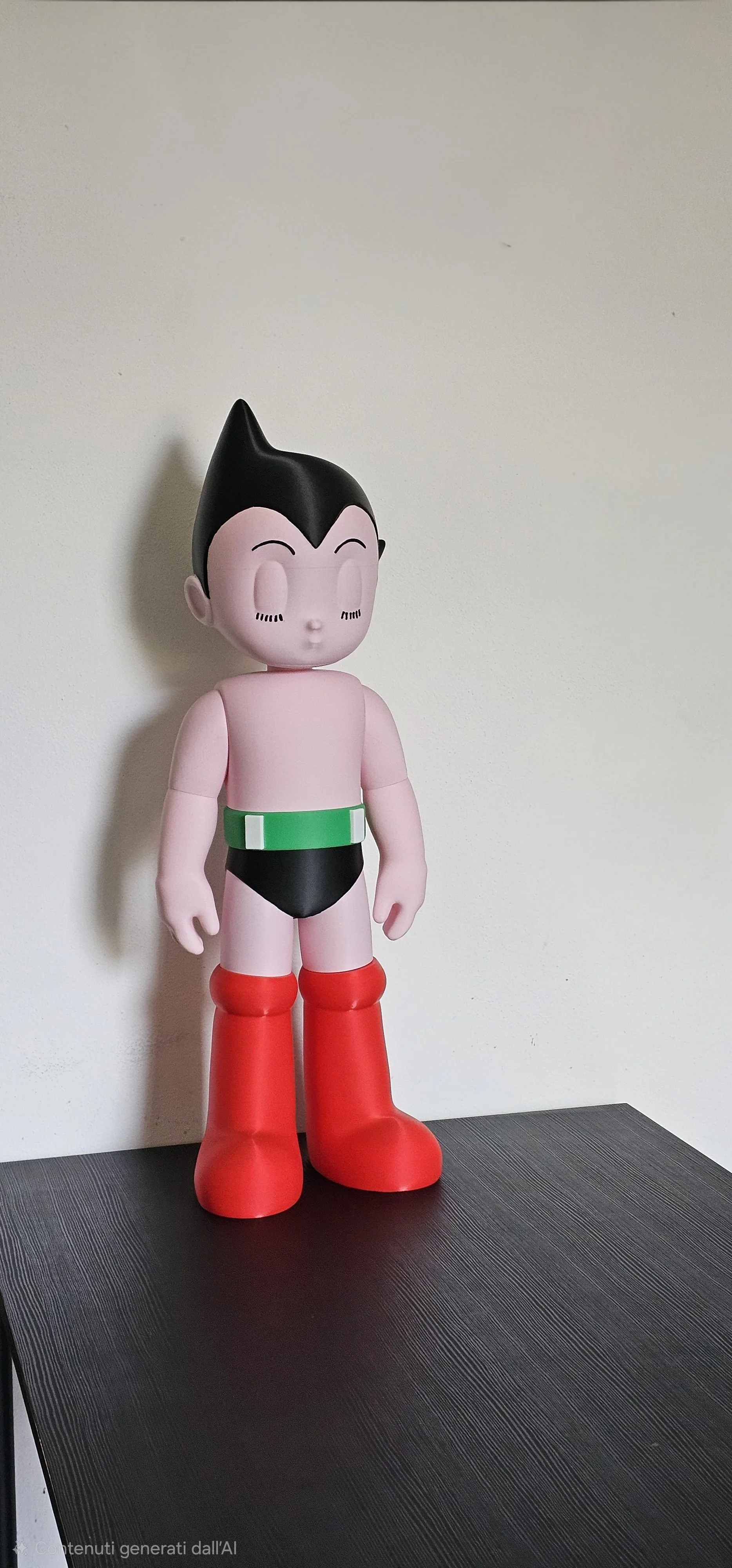 Statua di un personaggio di cartoon con capelli neri a punta, corpo rosa, indossa un costume da nuotatore con un bikini nero, cintura verde e stivaletti rossi.