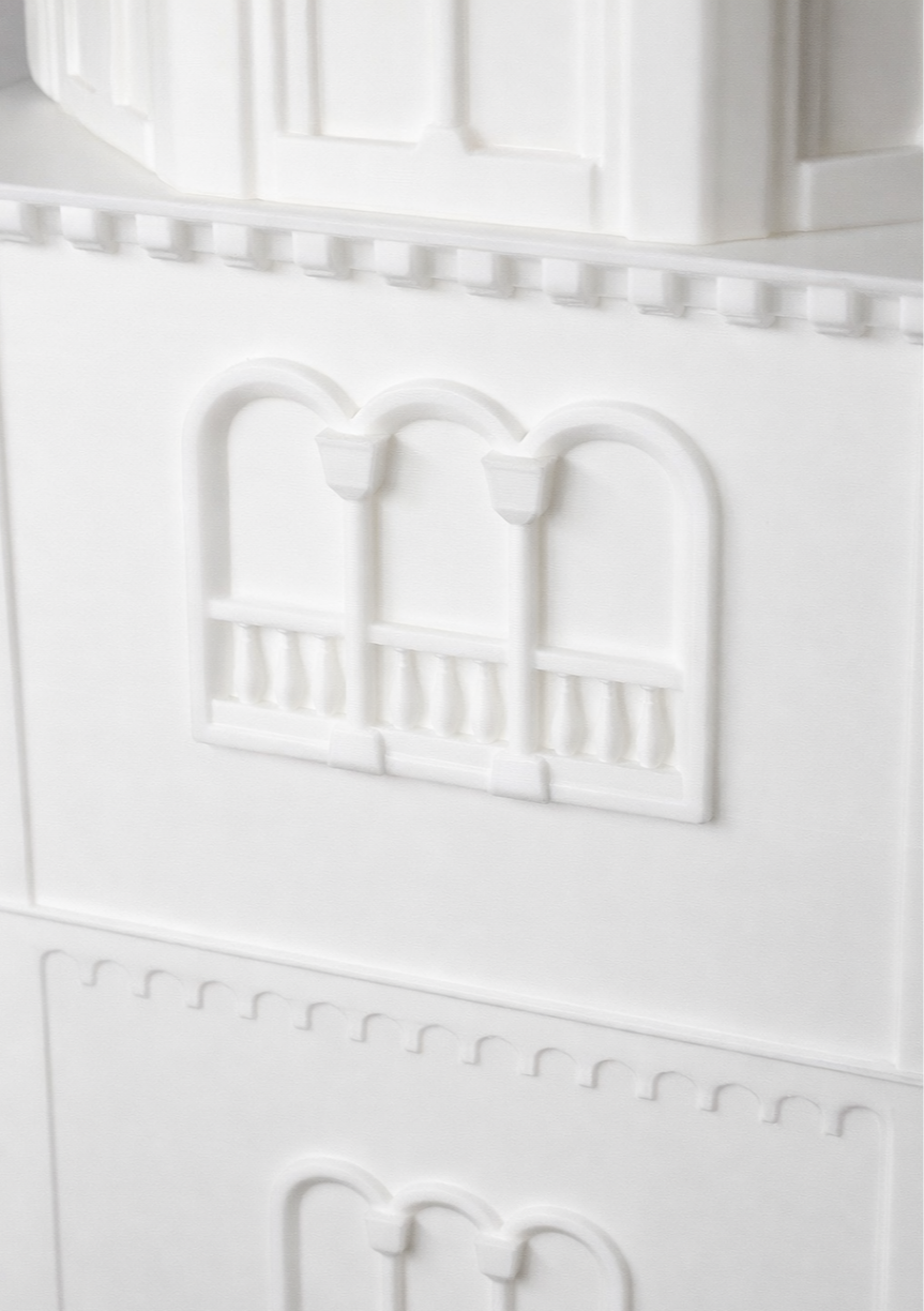 Dettaglio di una parete bianca con decorazioni in rilievo a forma di piccole archi e battuta.