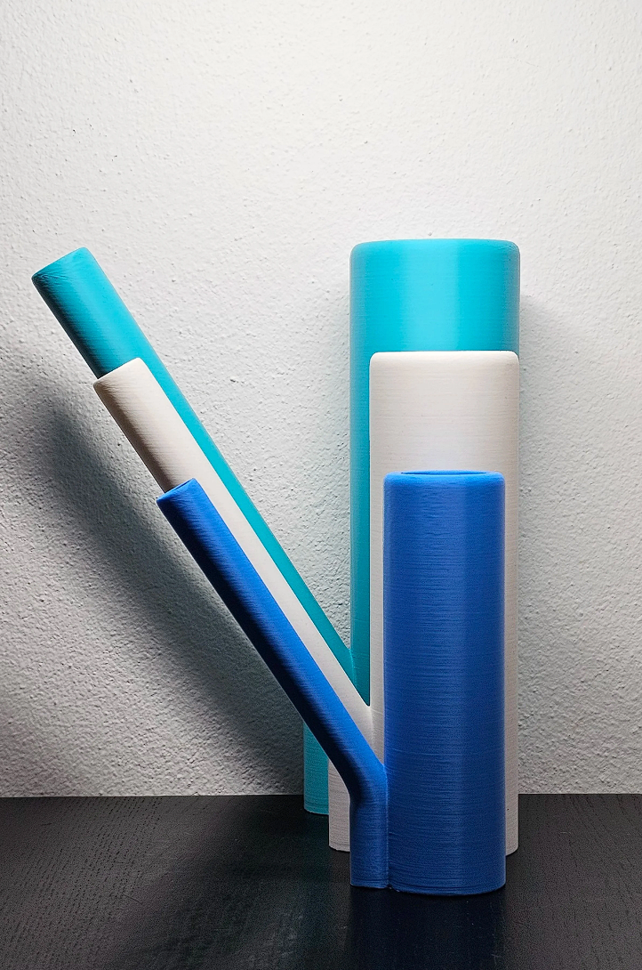 Diversi rotoli di pellicola adesiva colorata in vari toni di blu e bianco, disposti su una superficie nera con sfondo bianco.