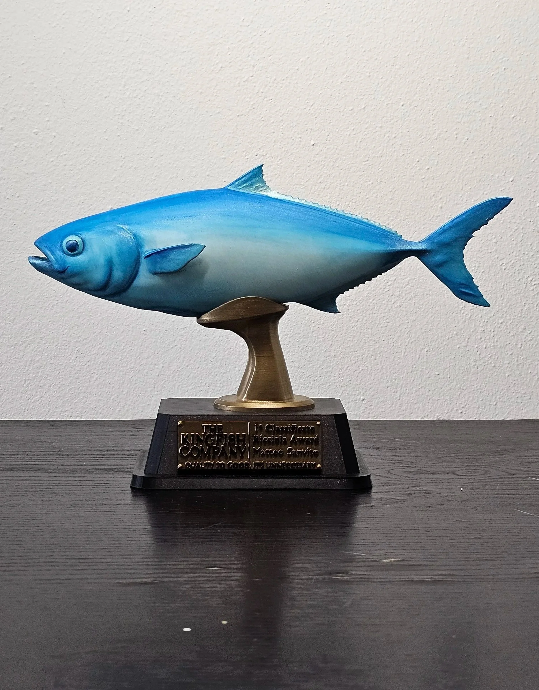 Statua di un pesce blu su un supporto di metallo con una placca commemorativa