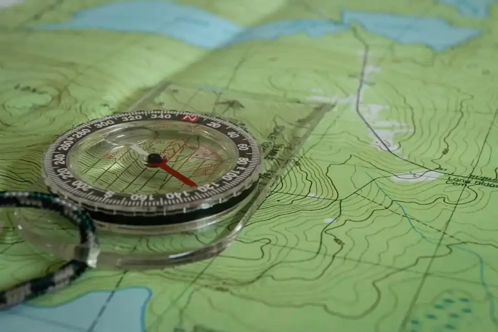 A topographic map with a compass placed on it, showing contour lines and terrain features.